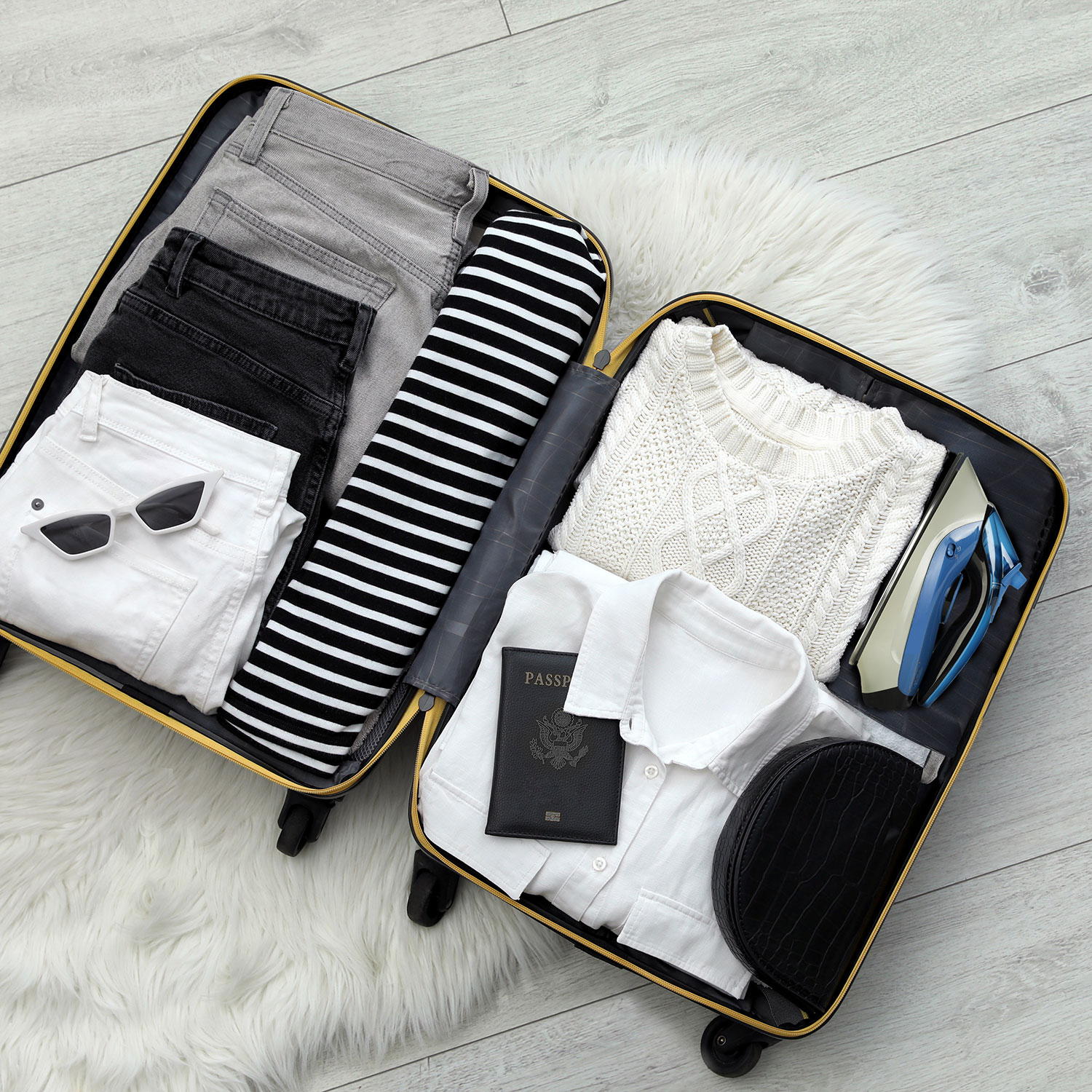 Walizka z ubraniami, okularami przeciwsłonecznymi, paszportem i żelazkiem.