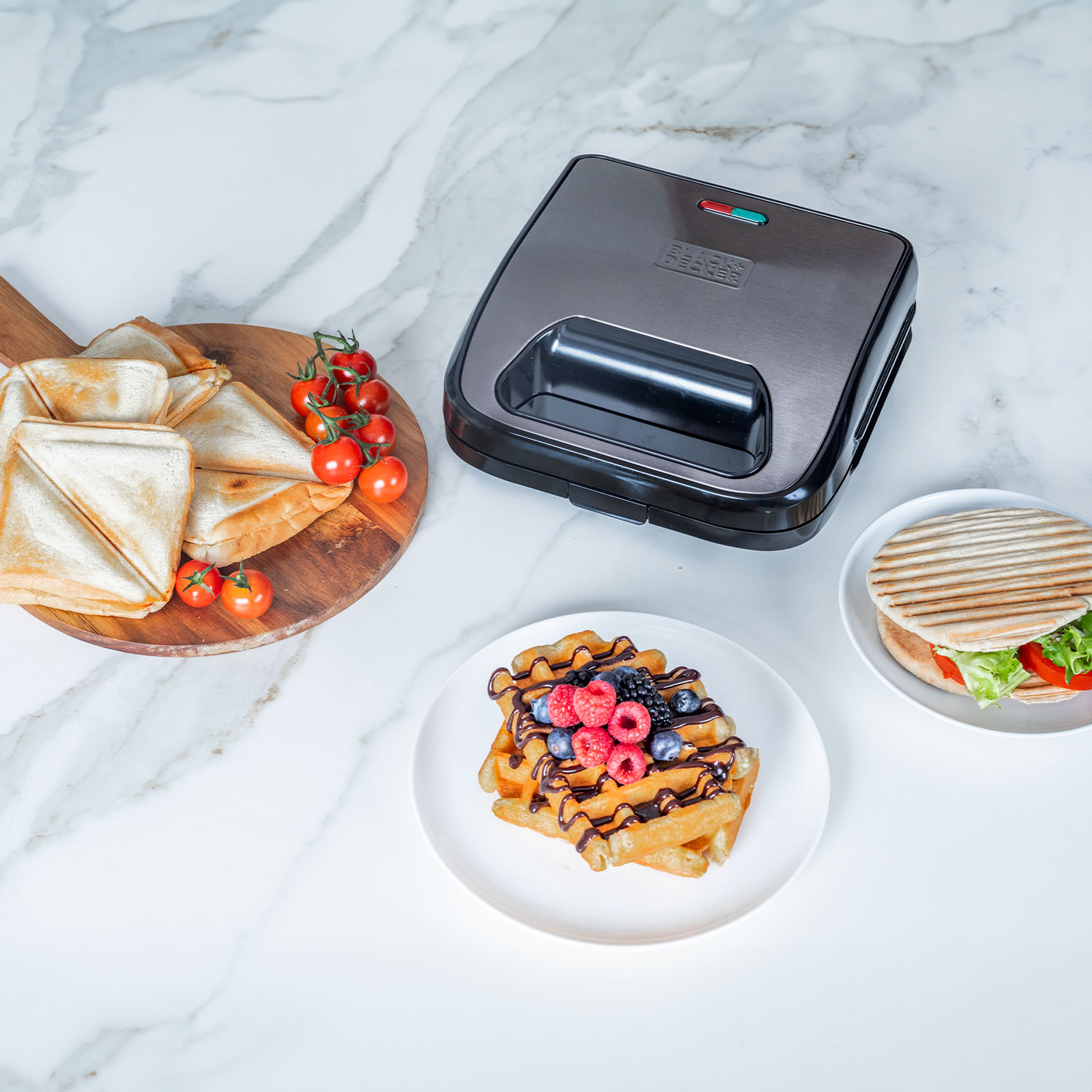 Gofrownica z goframi, jagodami i kanapką. Czarna maszyna jest w pobliżu.