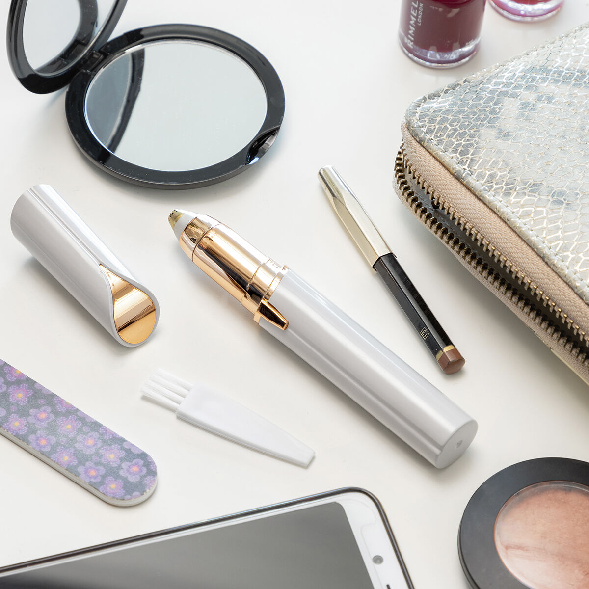 Kosmetika auf weißer Oberfläche: Spiegel, Beauty-Tools, Nagellack, Make-up-Tasche und Telefon.