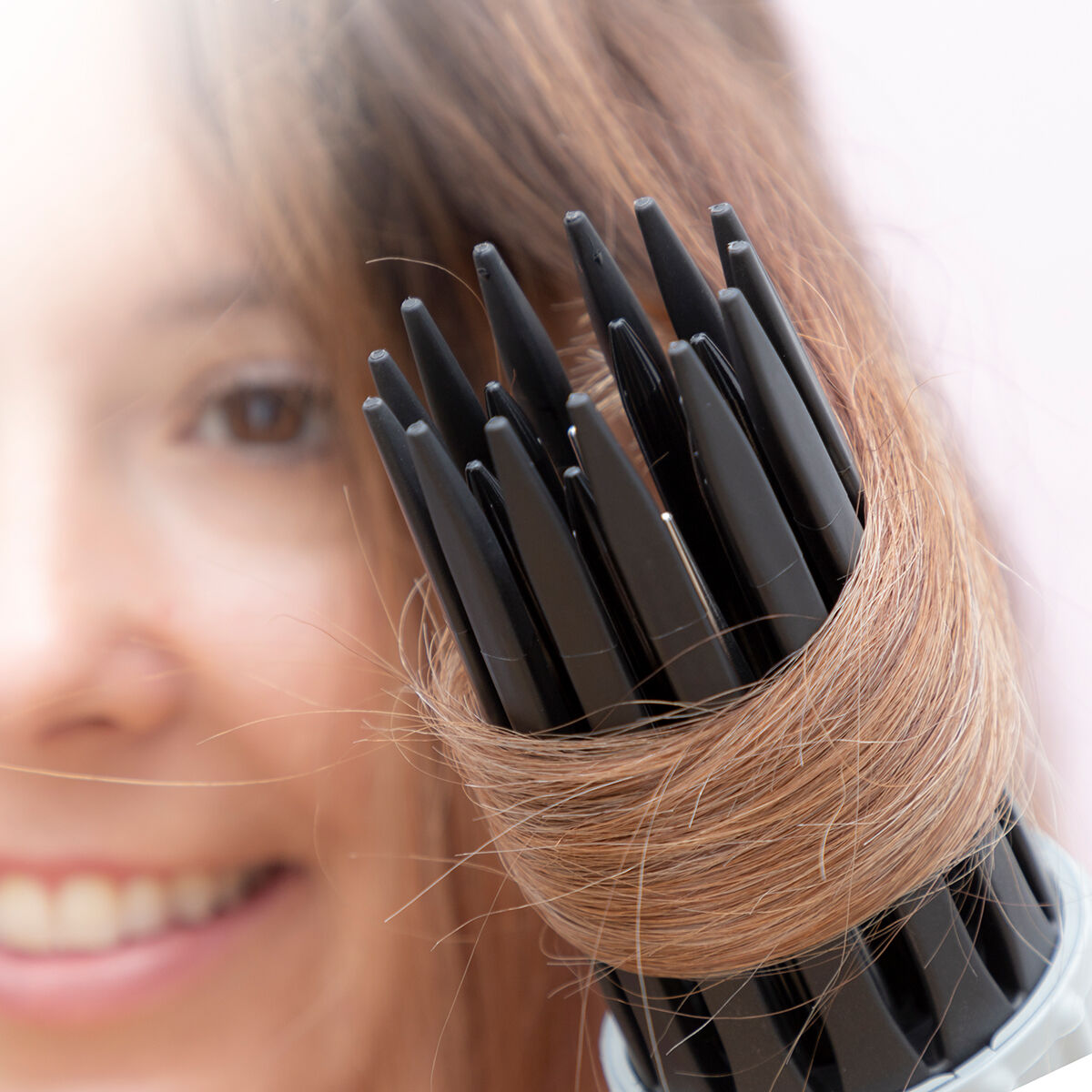 Il viso di una donna è sfocato, con uno strumento per capelli nei suoi capelli. Lo strumento ha setole nere.