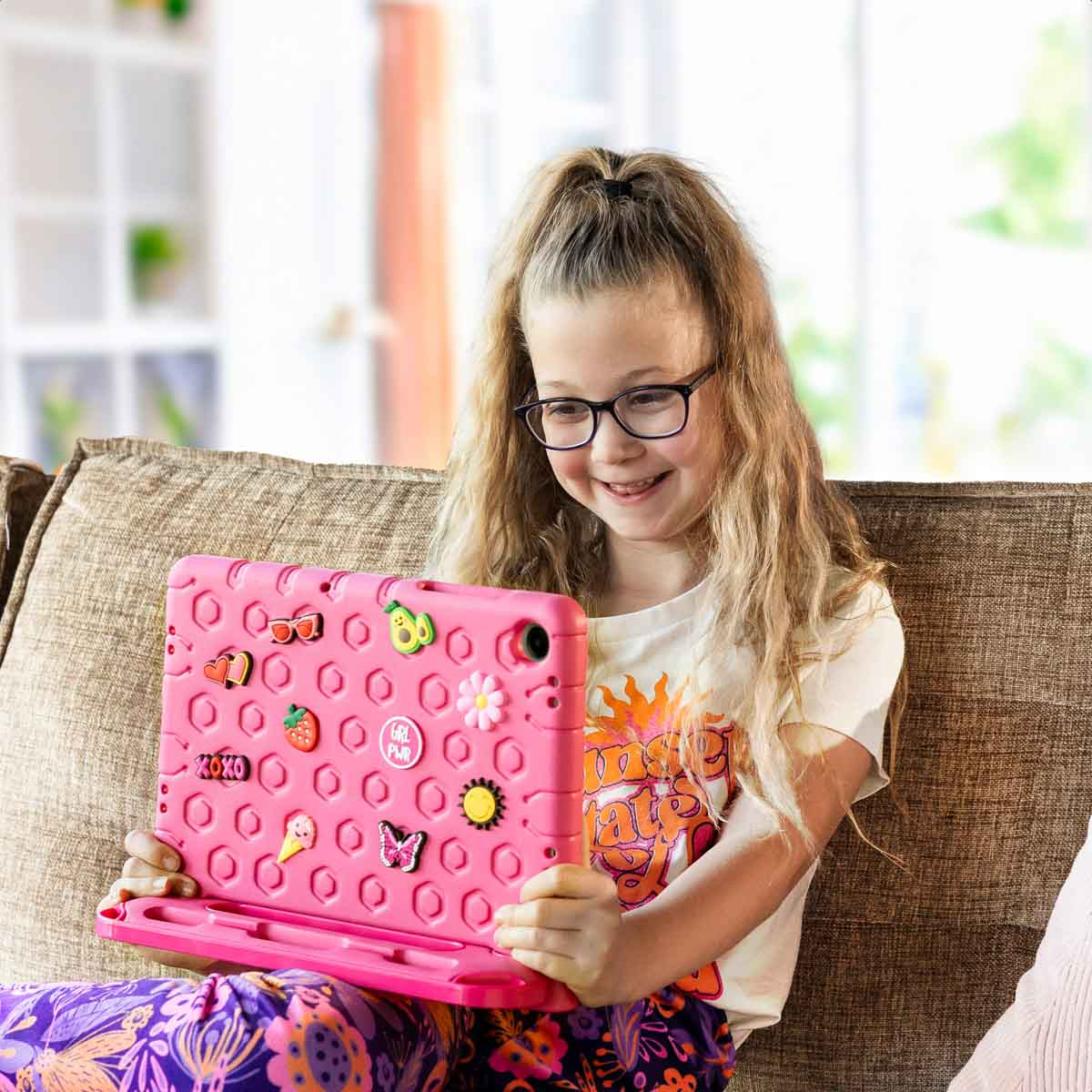 Girl with glasses holding a pink tablet in a pink case with stickers.