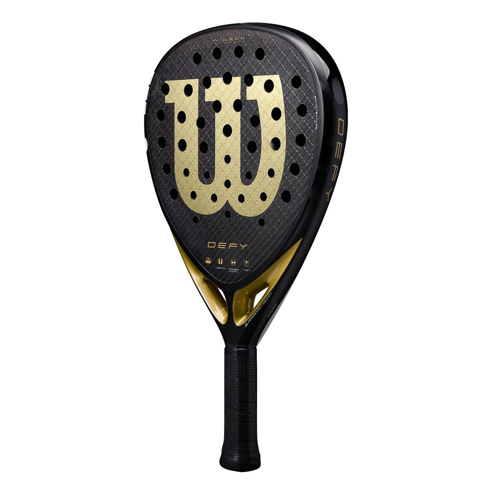Una pala de pádel Wilson negra y dorada. El logo 'W' es visible, junto con 'DEFY'. El mango es negro.