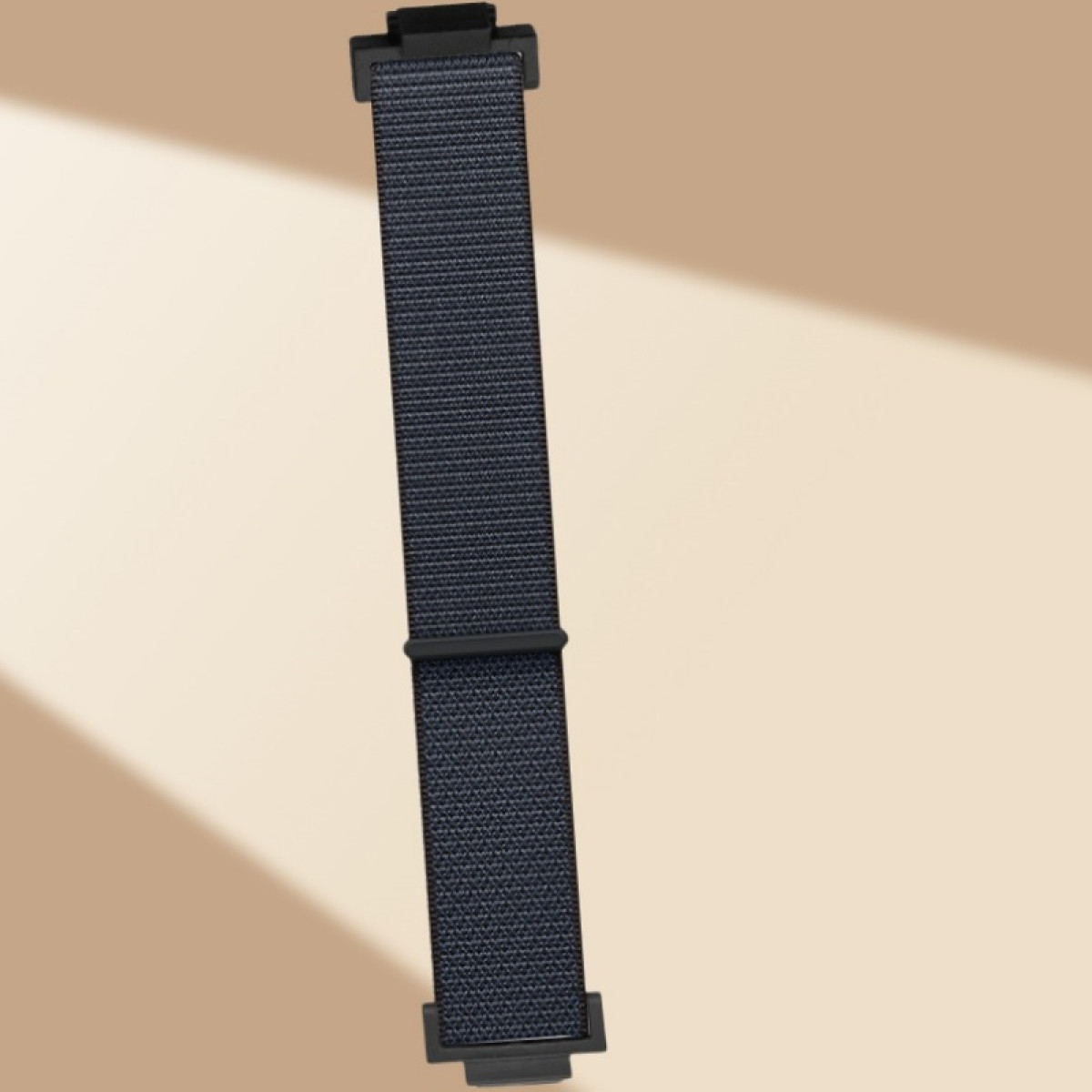 Marineblaues Uhrenarmband mit schwarzen Verschlüssen. Band ist gerade und vor einem beigen Hintergrund abgewinkelt.