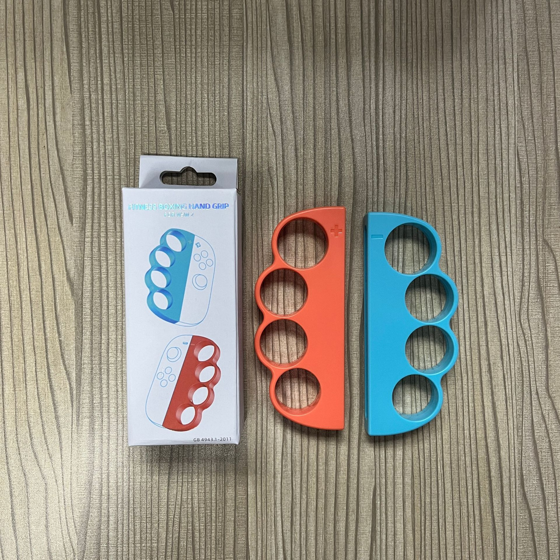 Zwei Gamecontroller in Orange und Blau.  Eine Box befindet sich links.  Holzhintergrund.