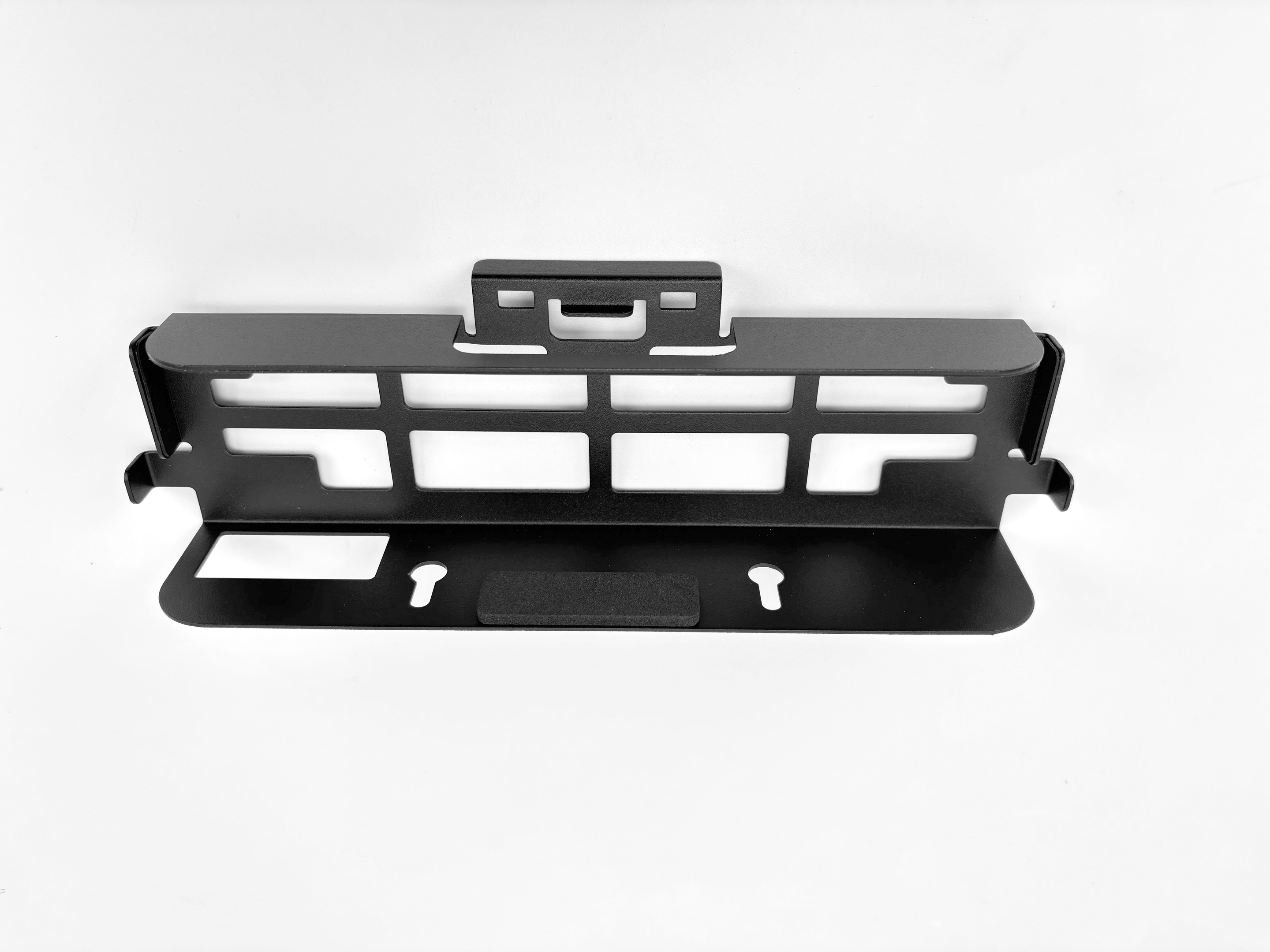 Czarny metalowy wspornik z wycięciami i uchwytem, na białej powierzchni.