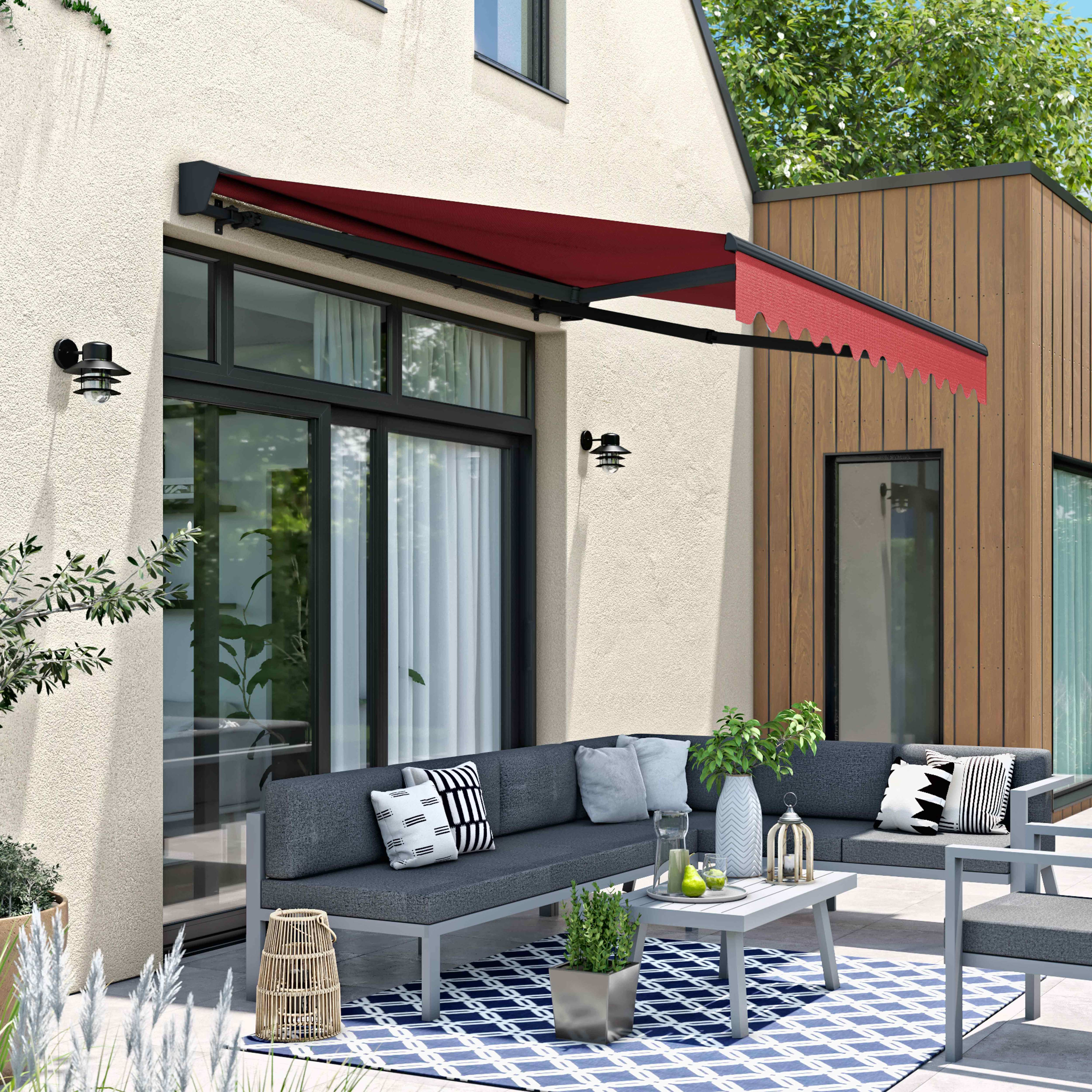 Szene im Freien: ein Haus mit Terrasse, Markise, Möbeln und blau gemustertem Teppich.