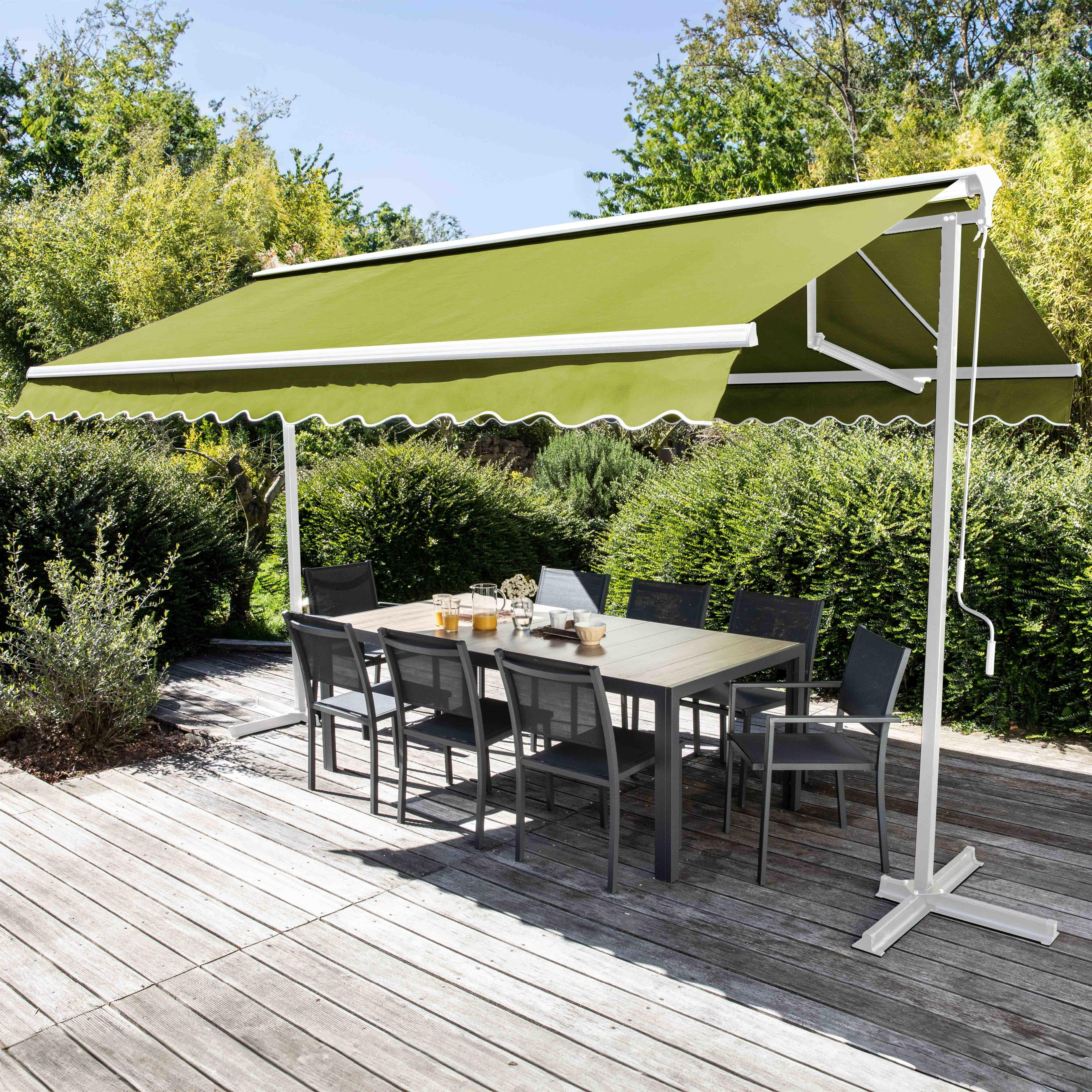 Terrassenszene: grüne Markise, Tisch mit Stühlen, Holzdeck und Bäume.