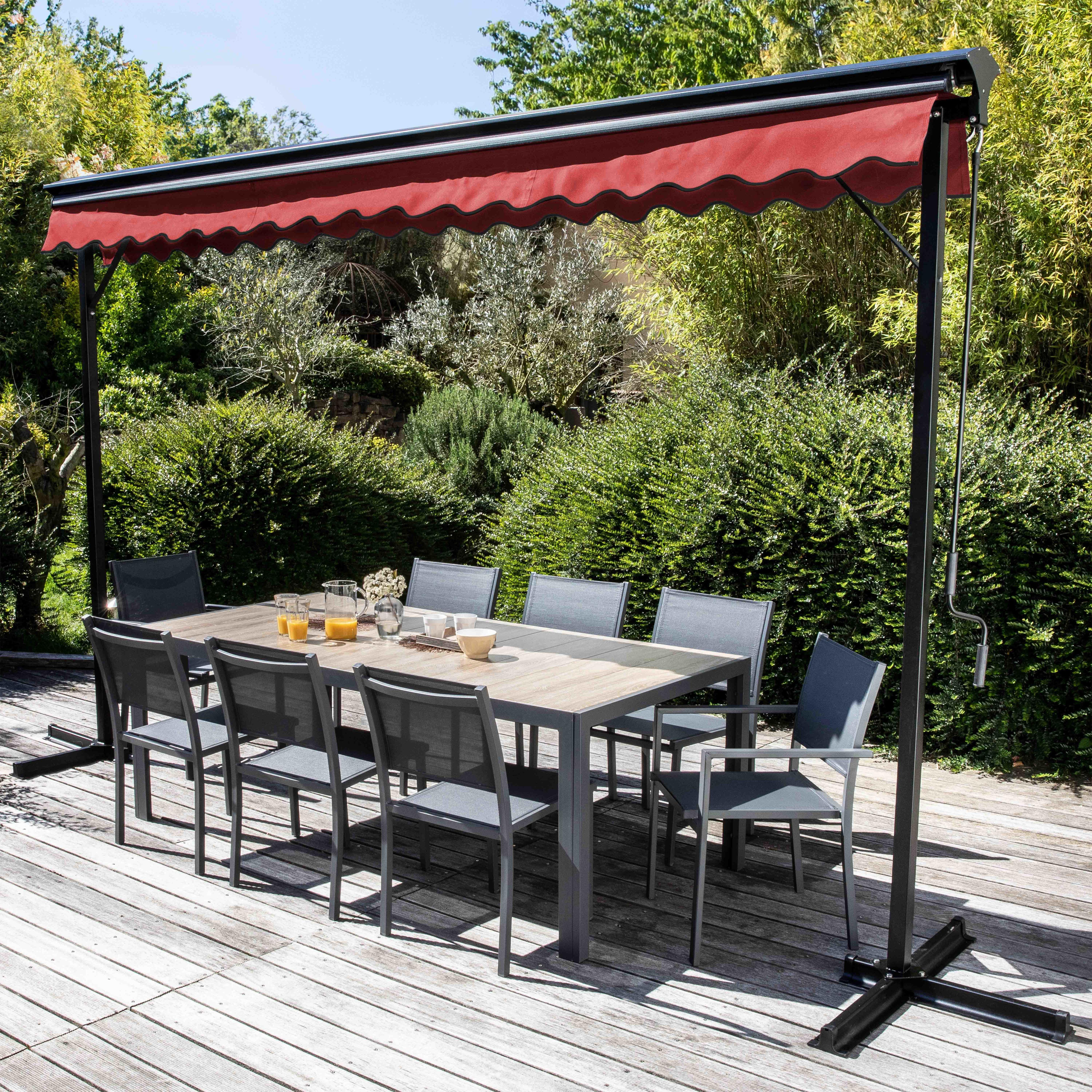 Essbereich im Freien: Tisch, Stühle, rotes Vordach, Essen, Getränke. Grüner Hintergrund, Holzterrasse.