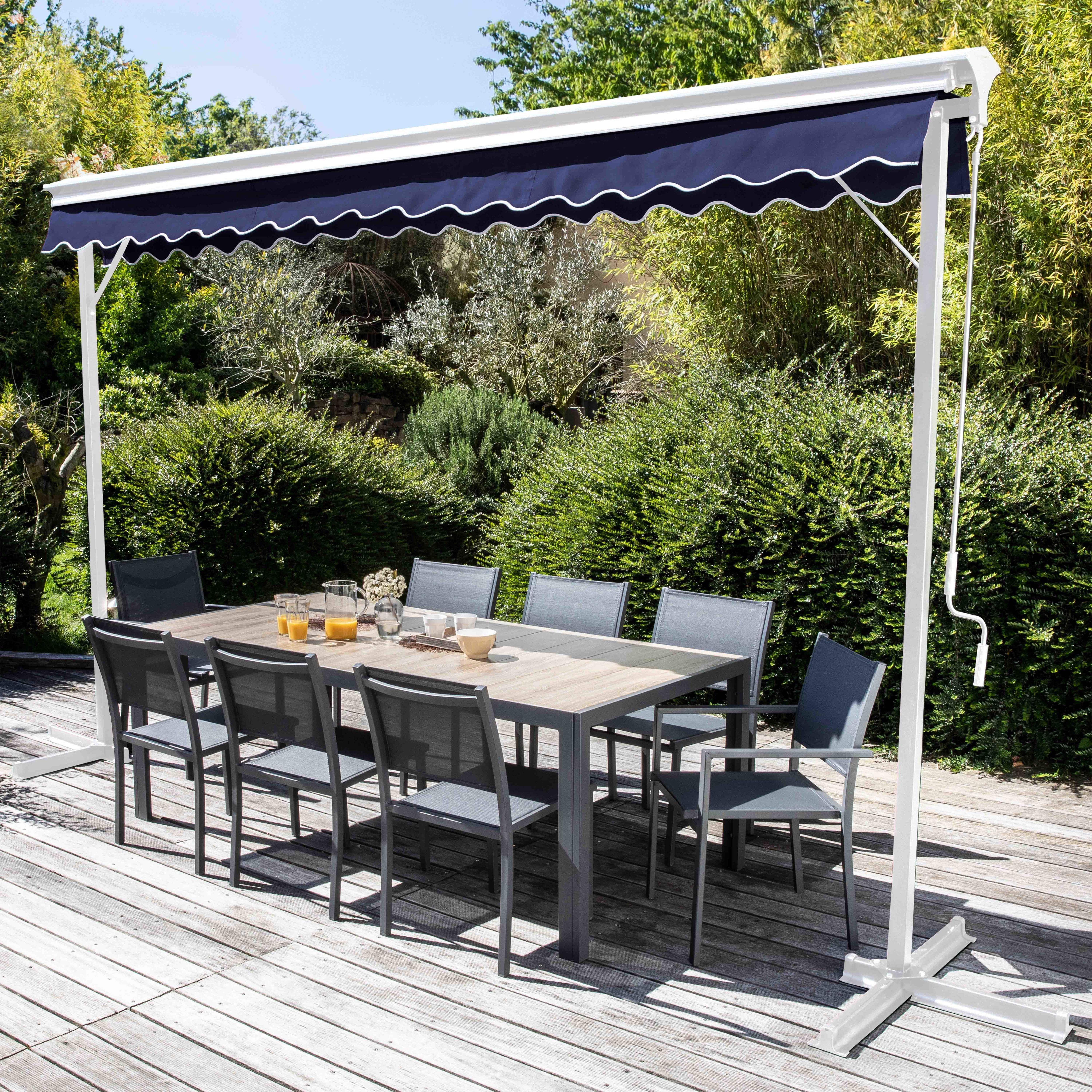 Gartenmöbel unter einer blauen Markise mit Grün, einer Holzterrasse und einem grauen Esszimmer-Set.