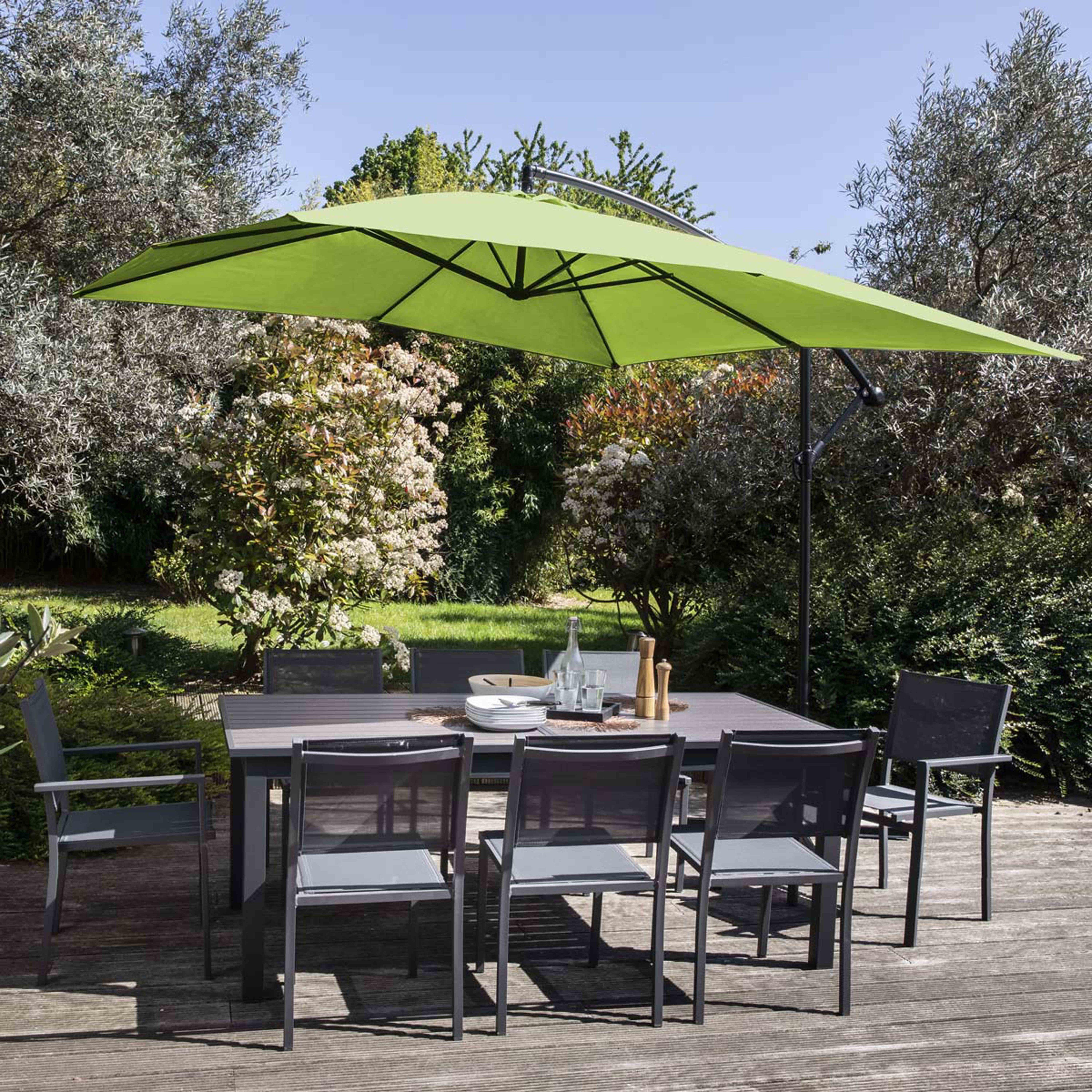Outdoor-Essgruppe mit grünem Sonnenschirm, Tisch und sechs Stühlen auf einer Holzterrasse, umgeben von üppigem Grün.
