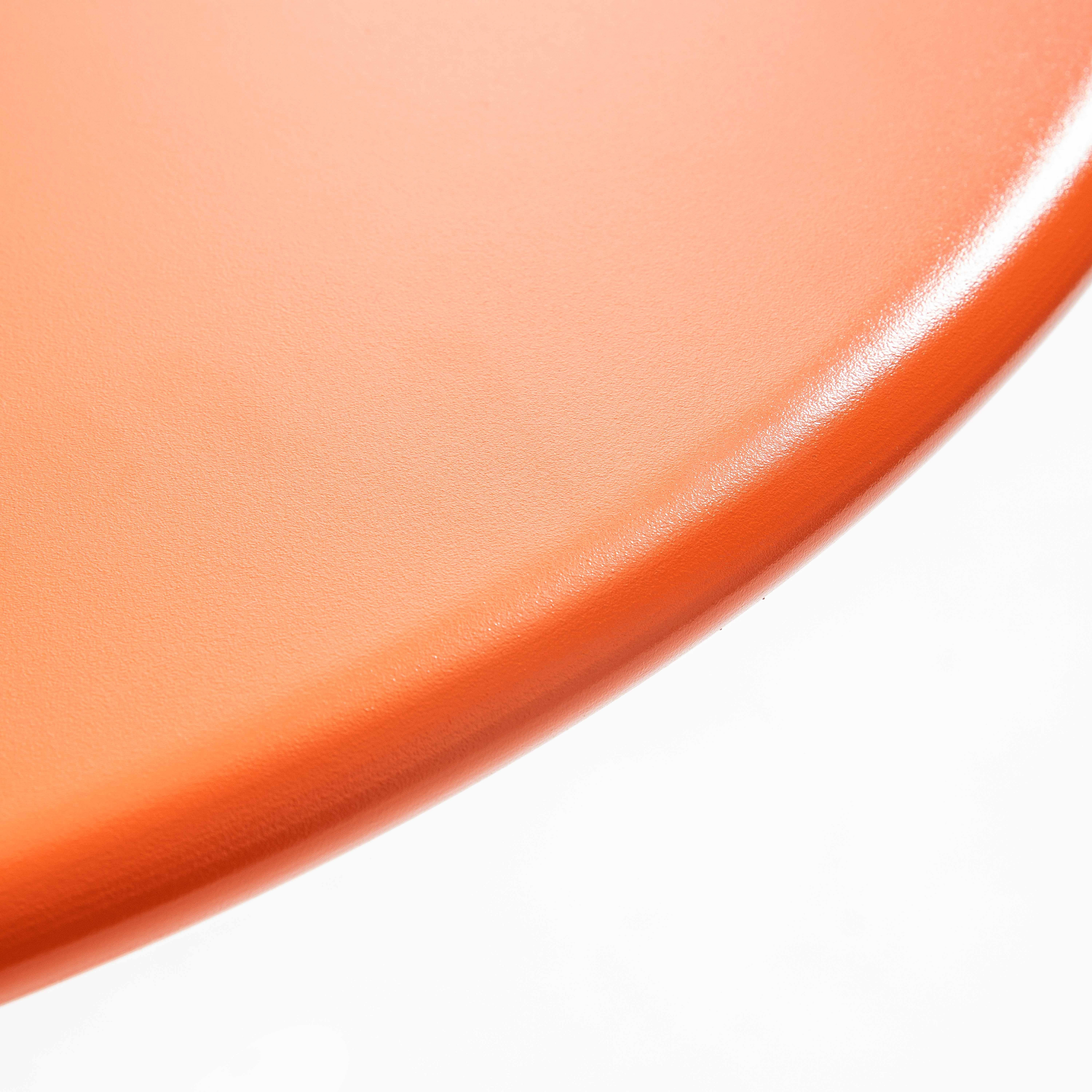 Nahaufnahme der orangefarbenen, strukturierten Oberfläche eines Tisches.
