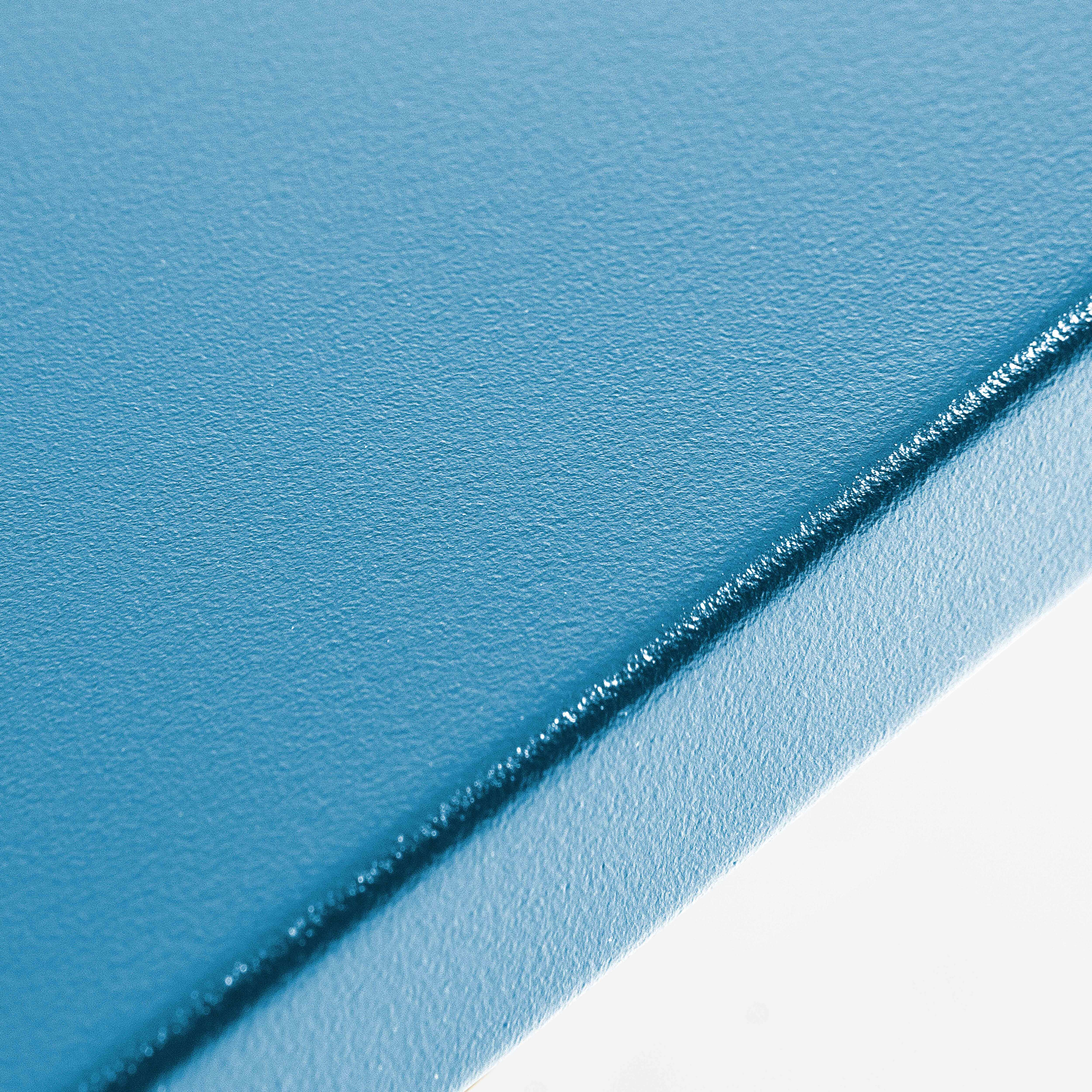 Nahaufnahme einer blauen Tischoberfläche, die Textur und Kante zeigt.