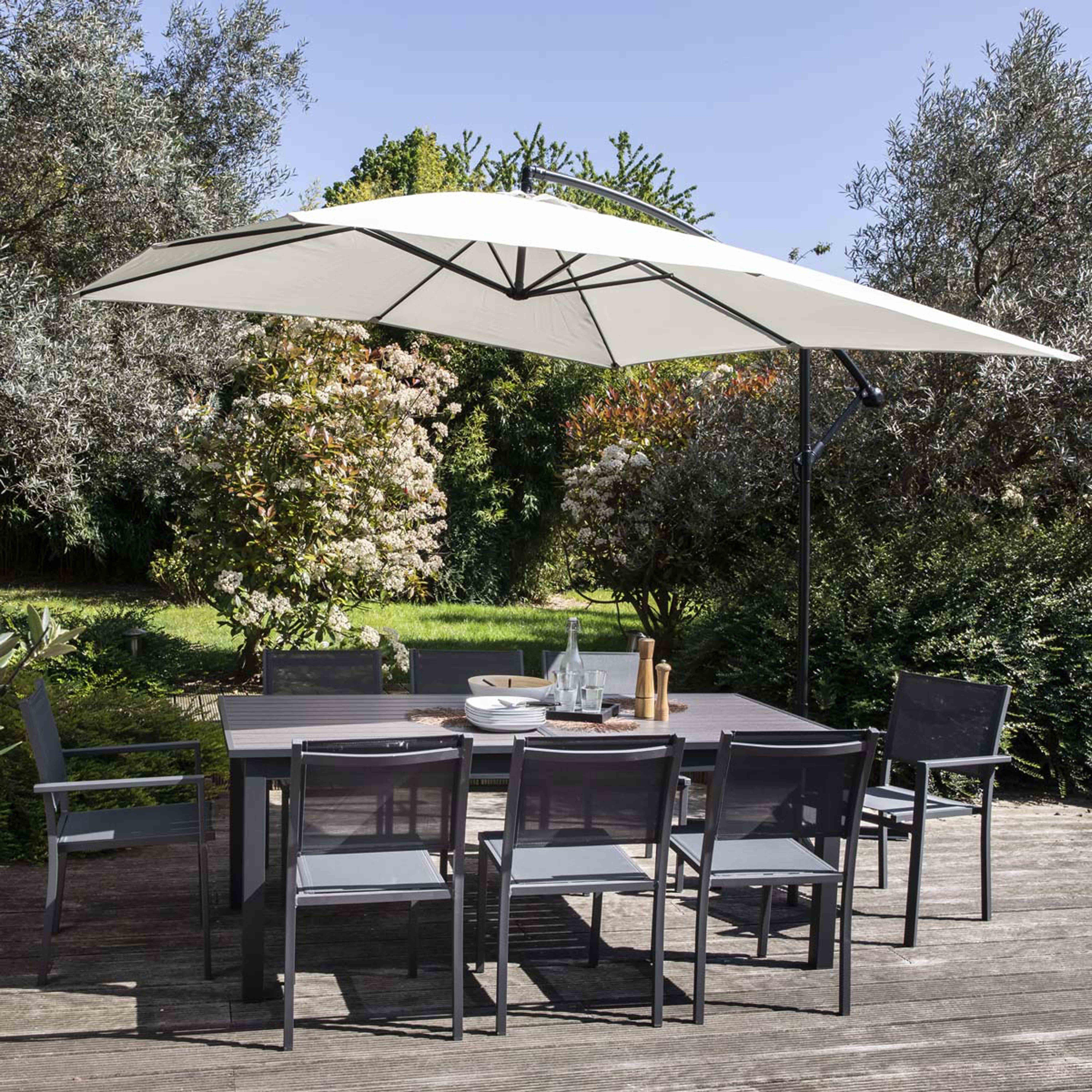 Essgruppe im Freien mit Sonnenschirm. Tisch, Stühle und sonnige Gartenkulisse.