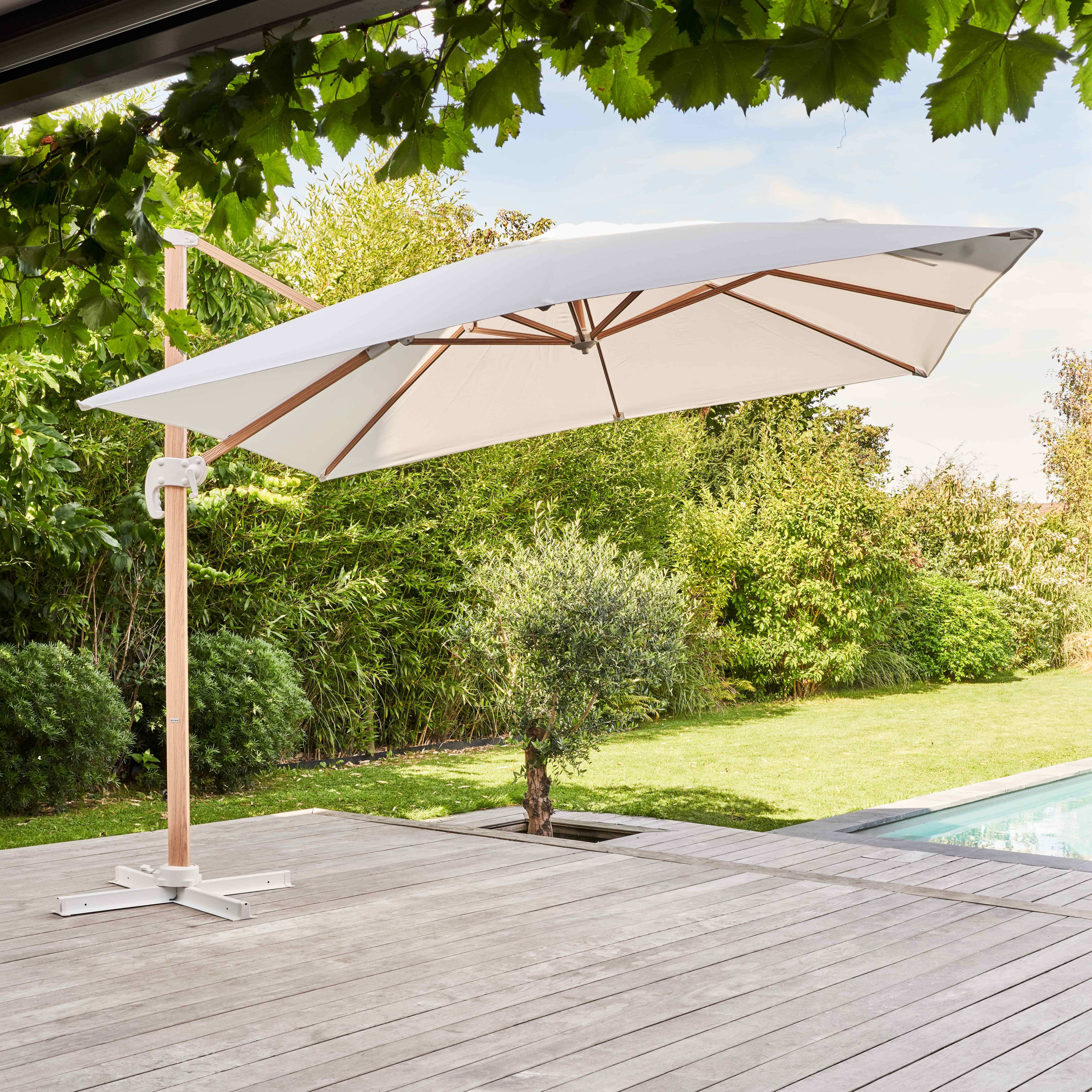 Weißer und holzgerahmter Ausleger-Sonnenschirm über Holzterrasse und Garten.