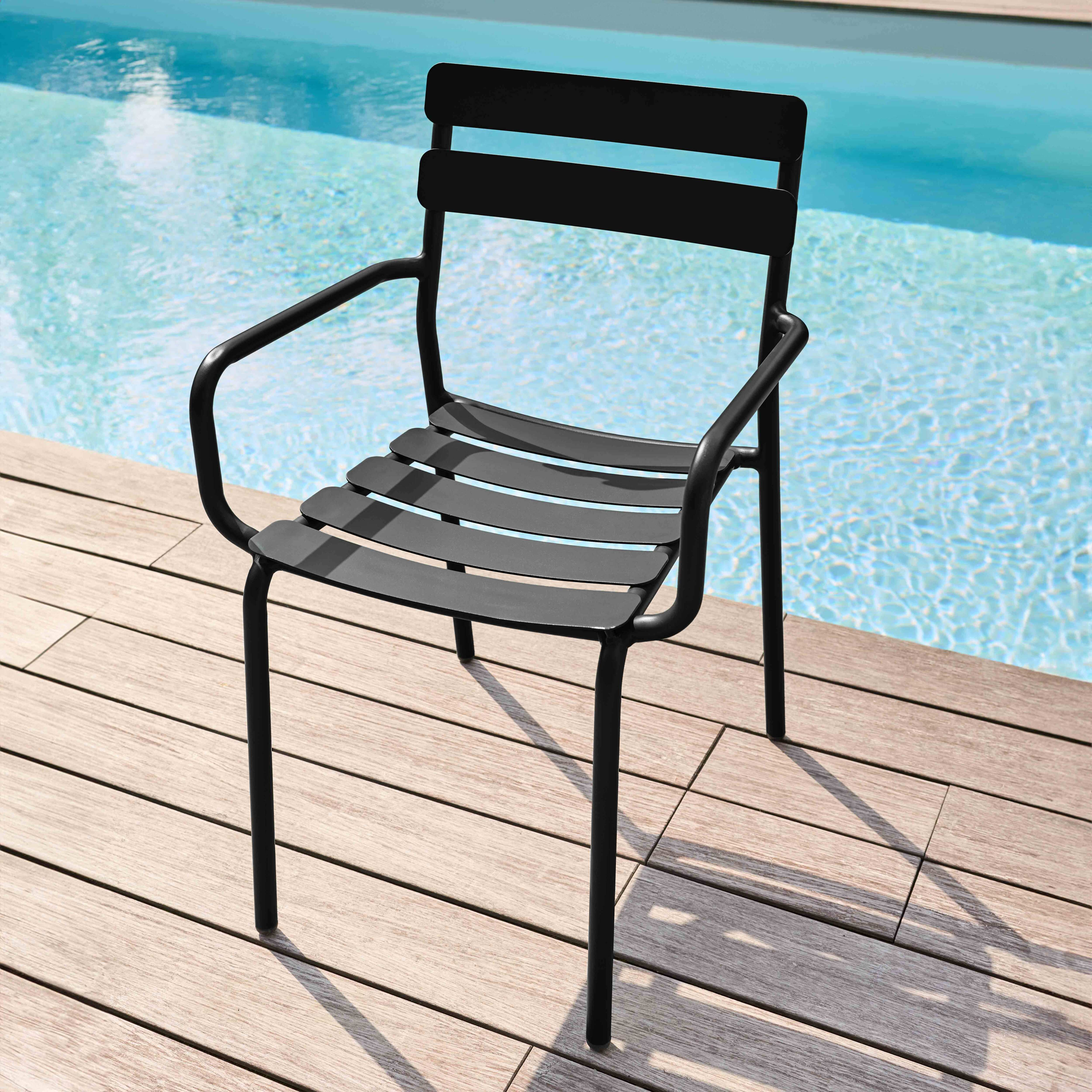 Schwarzer Metallstuhl mit Lattenrost am Pool mit blauem Wasser und Holzdeck.