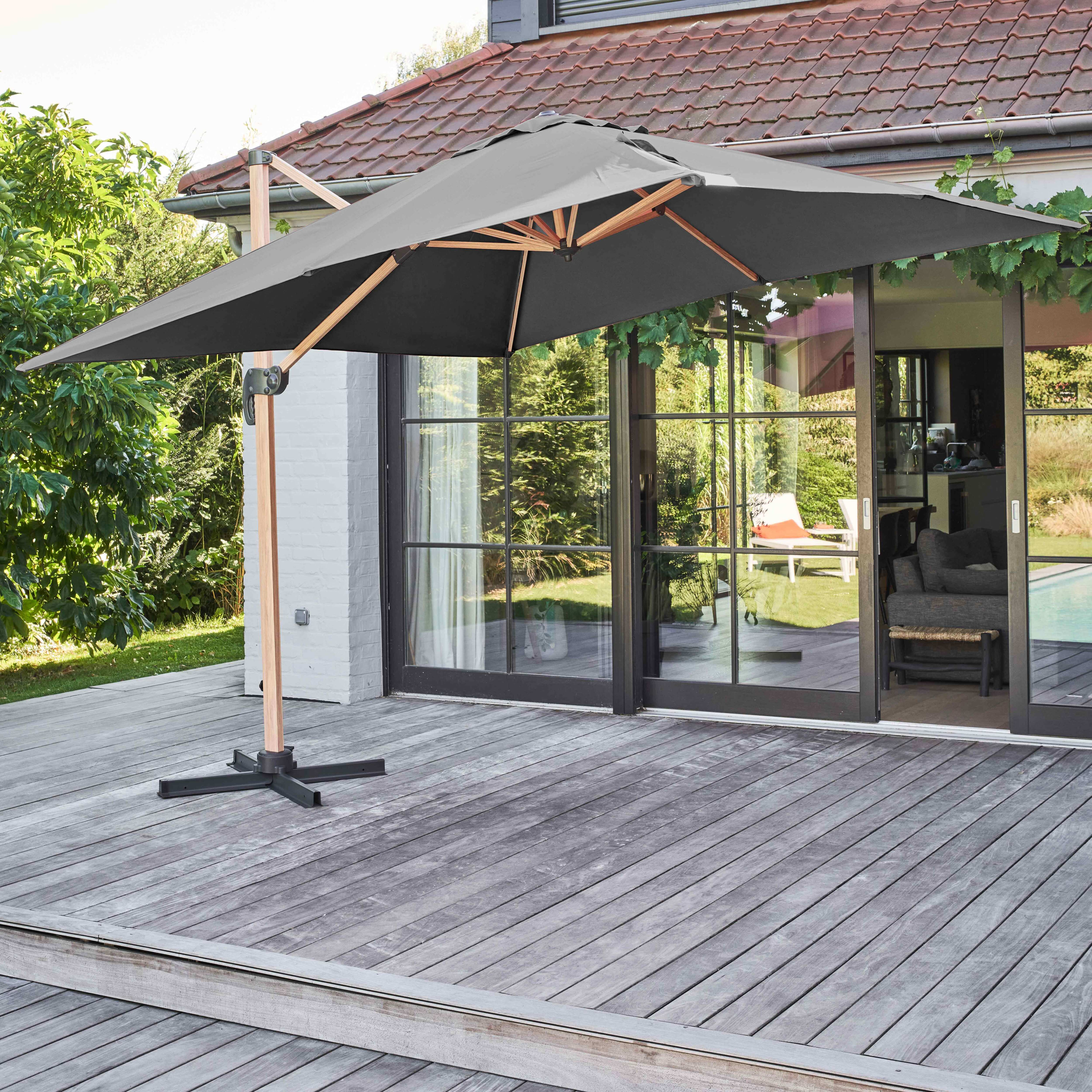 Grauer Sonnenschirm auf Holzterrasse mit Haus im Hintergrund.