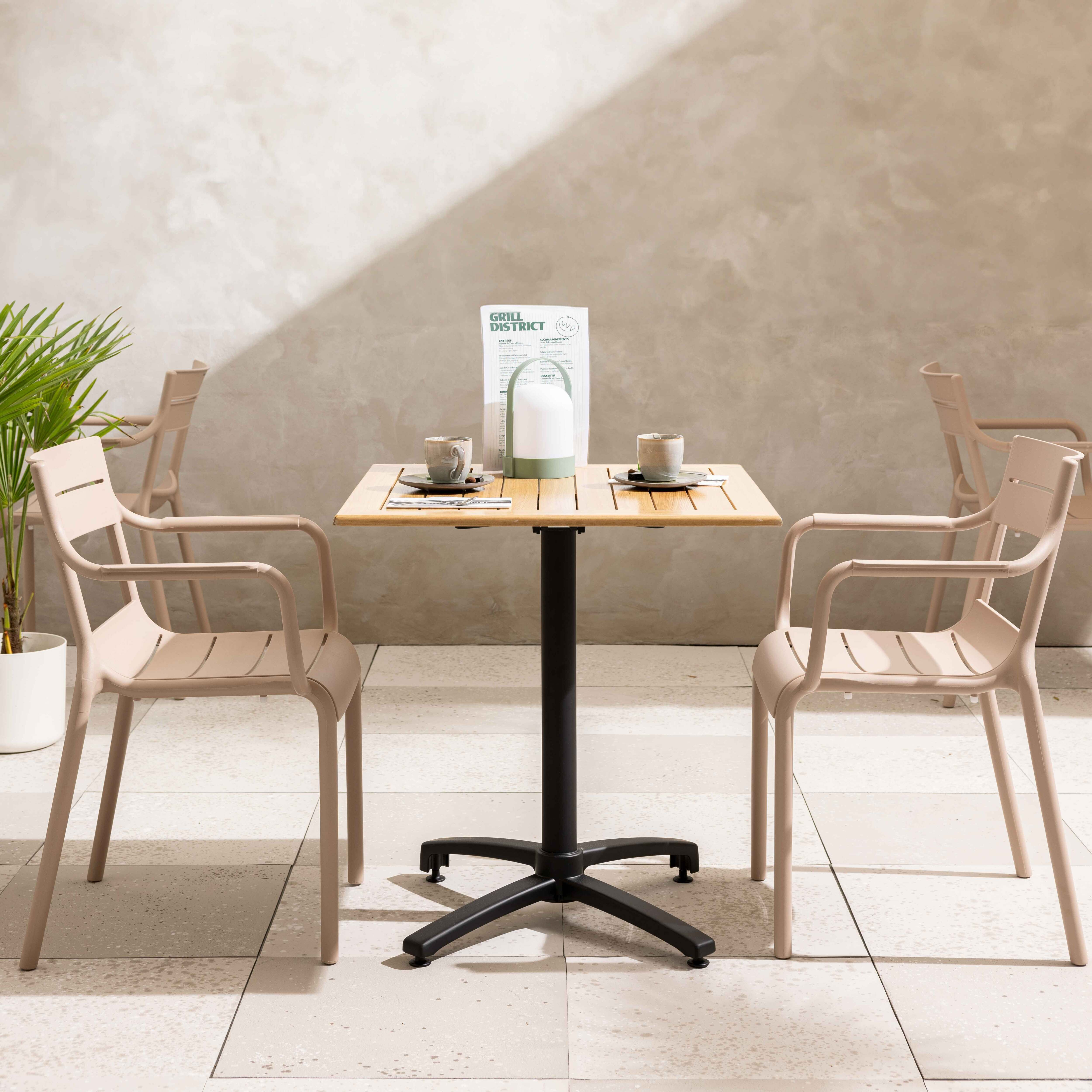 Ein Tisch mit zwei Stühlen. Eine Speisekarte und Tasse und Lampe auf dem Tisch. Beige Stühle, Steinboden.