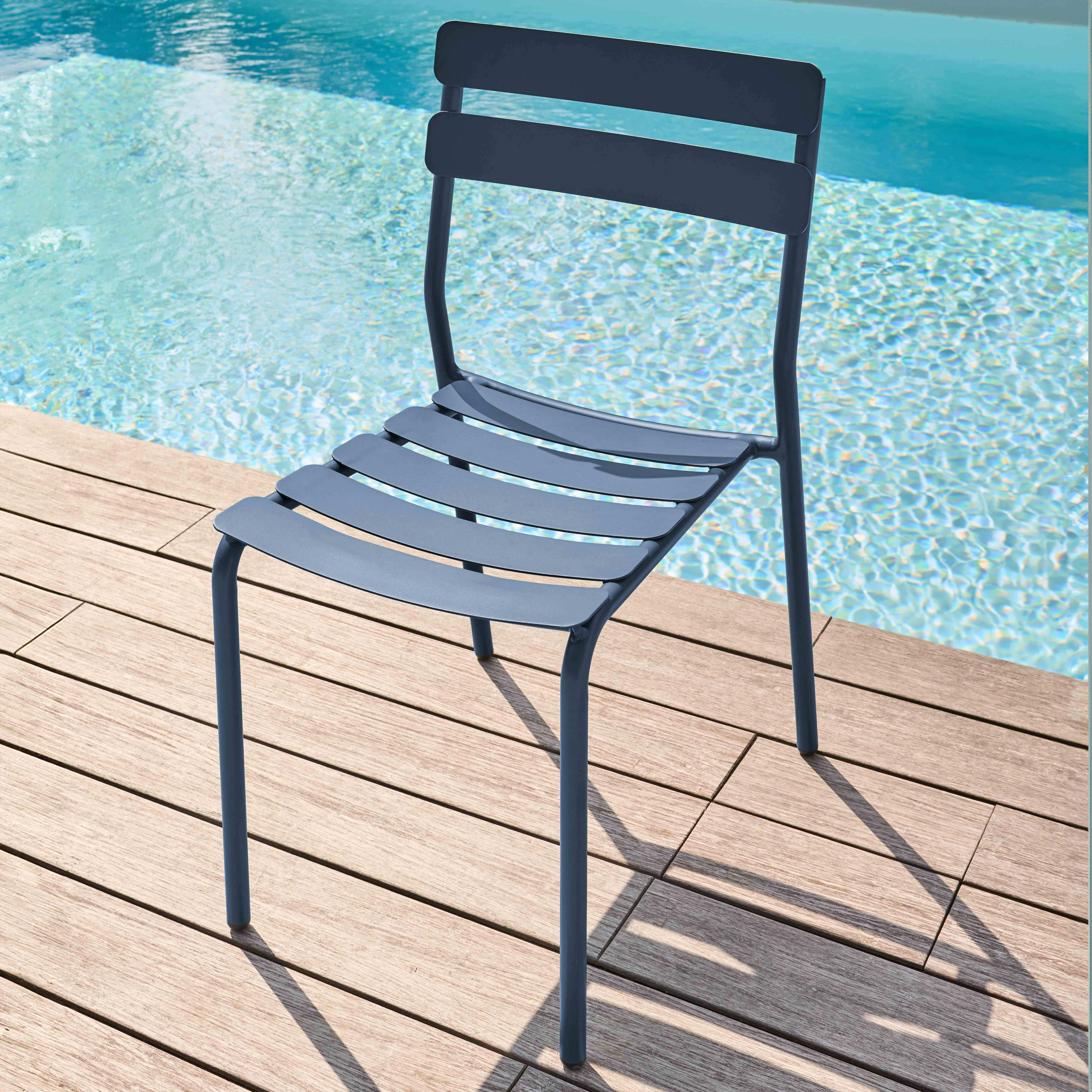 Blauer Stuhl am Pool, mit Holzdeck und Wasser im Hintergrund.