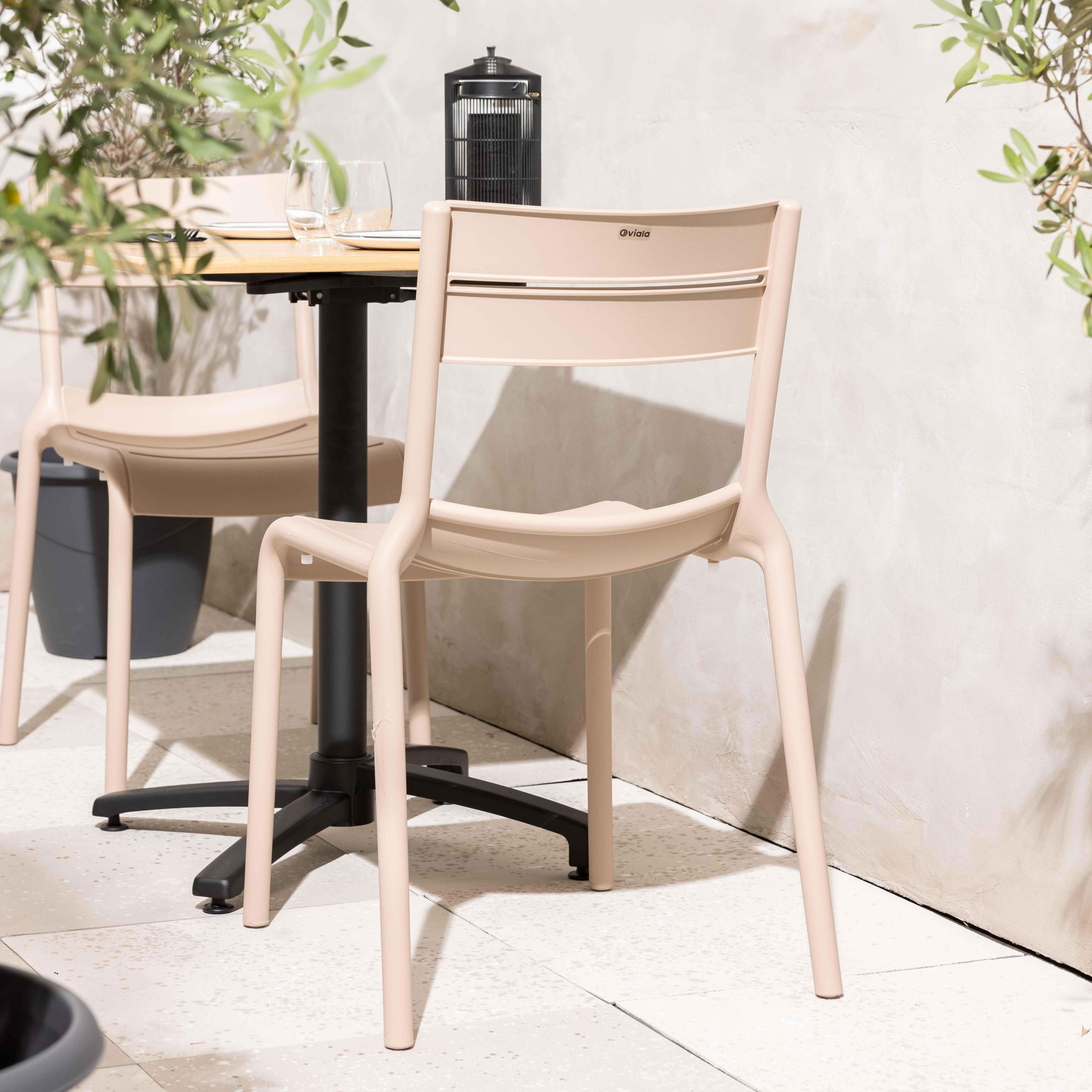 Zwei Stühle mit Tisch, Topf und Pflanzen. Die Szene ist im Freien.