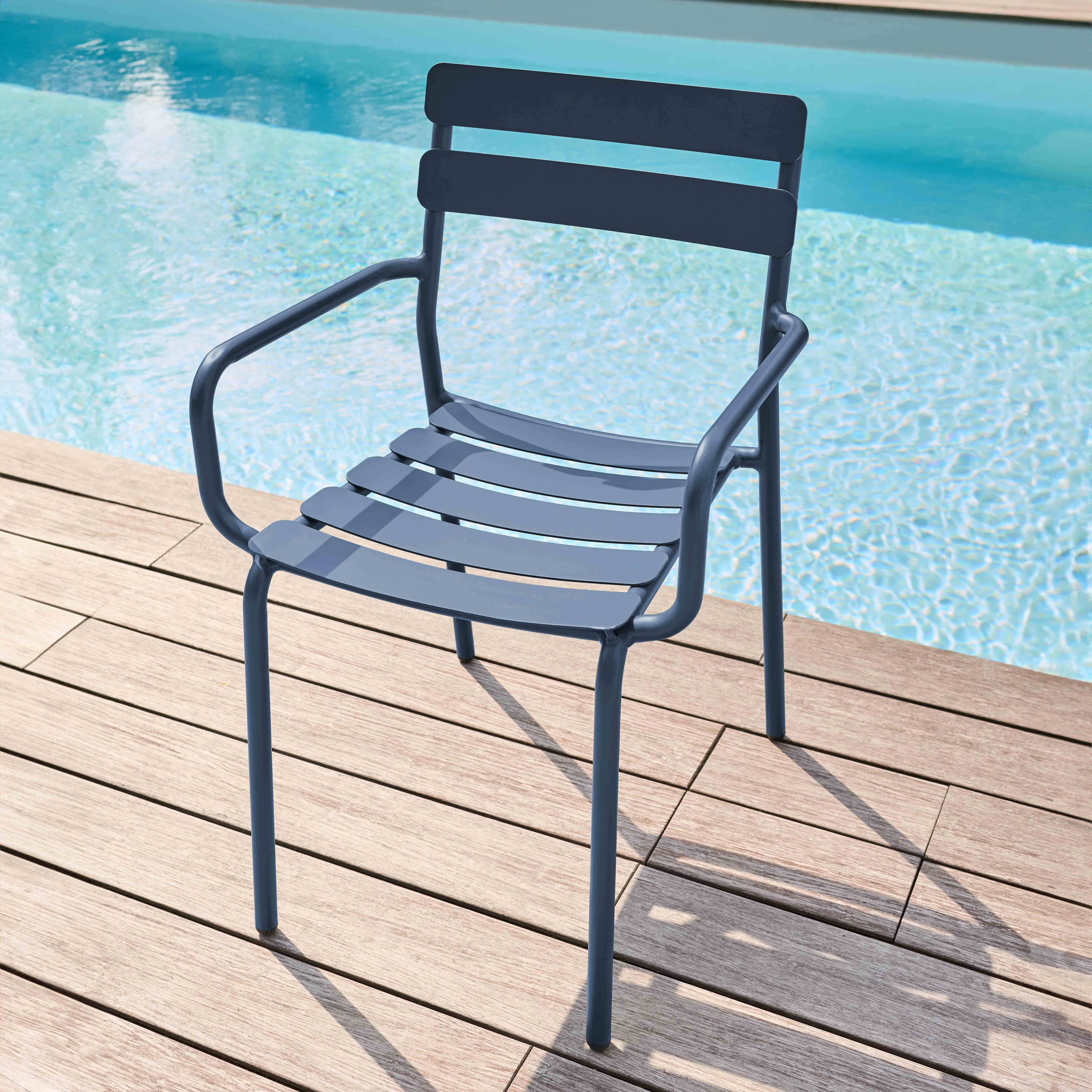 Ein blauer Stuhl mit Lamellenrücken und Armlehnen neben einem Pool.
