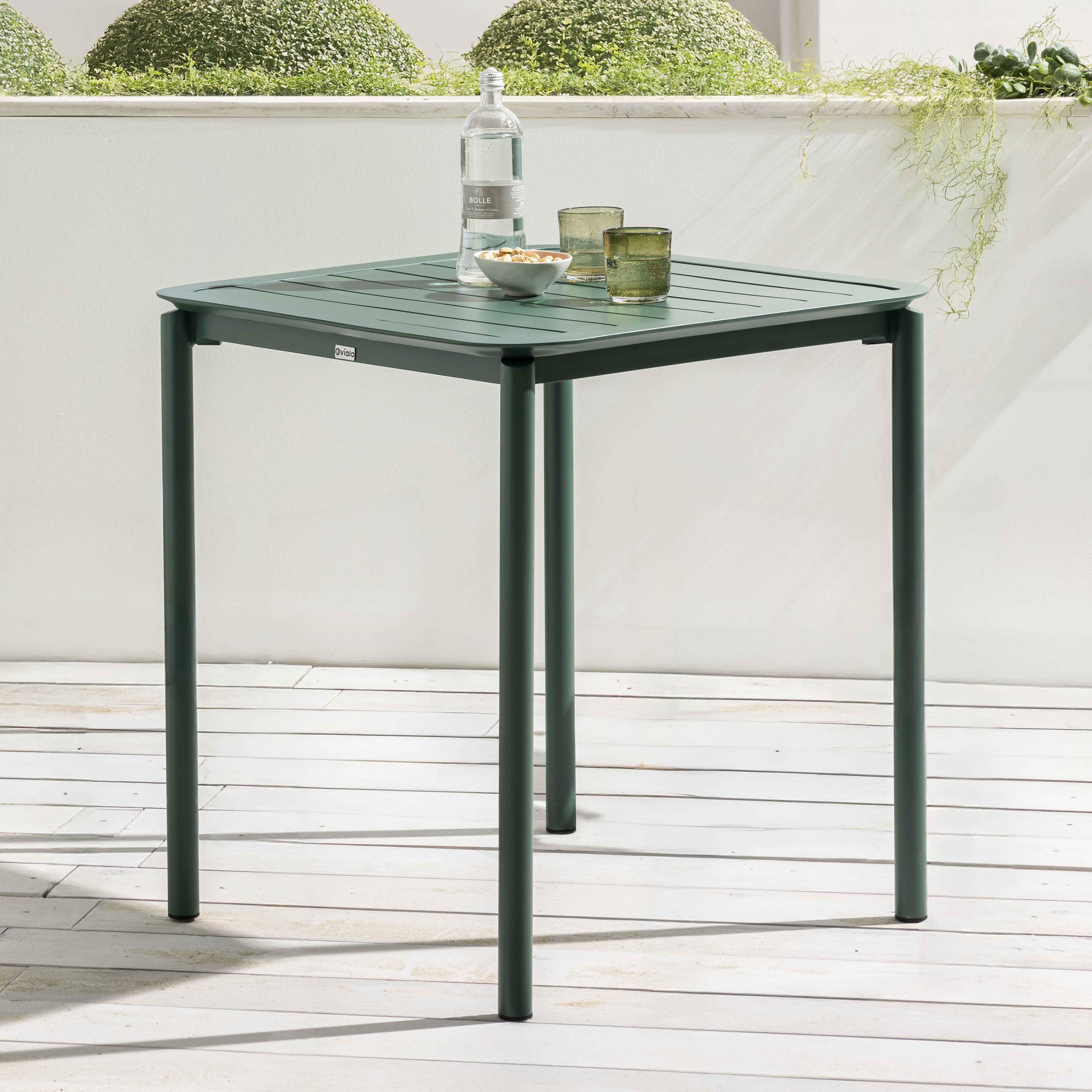 Quadratischer grüner Tisch mit Gläsern und einer Flasche. Pflanzen sind vorhanden. Weißer Hintergrund.