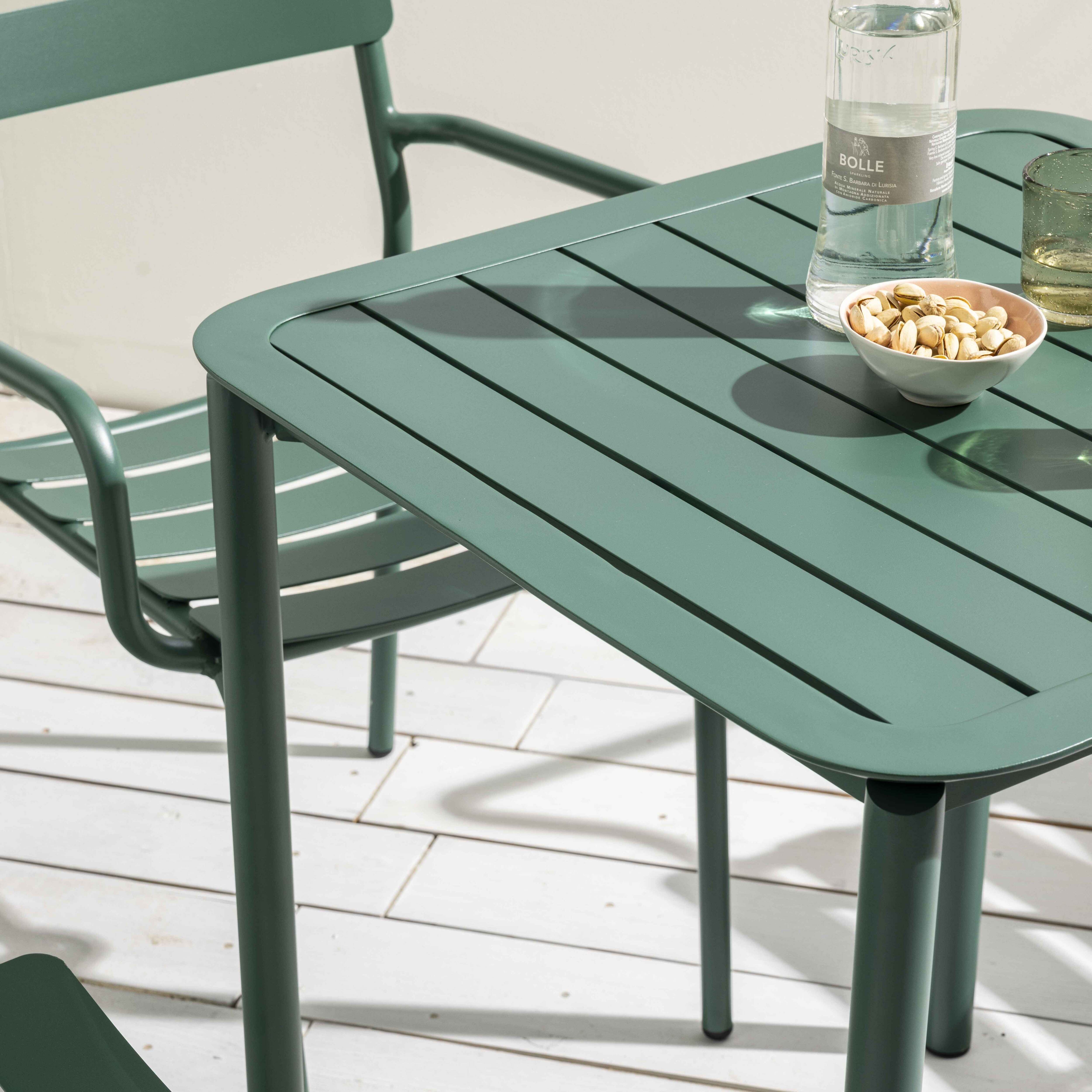 Grünes Tisch- und Stuhl-Set auf Holzterrasse, mit Wasserflasche und Pistazien.