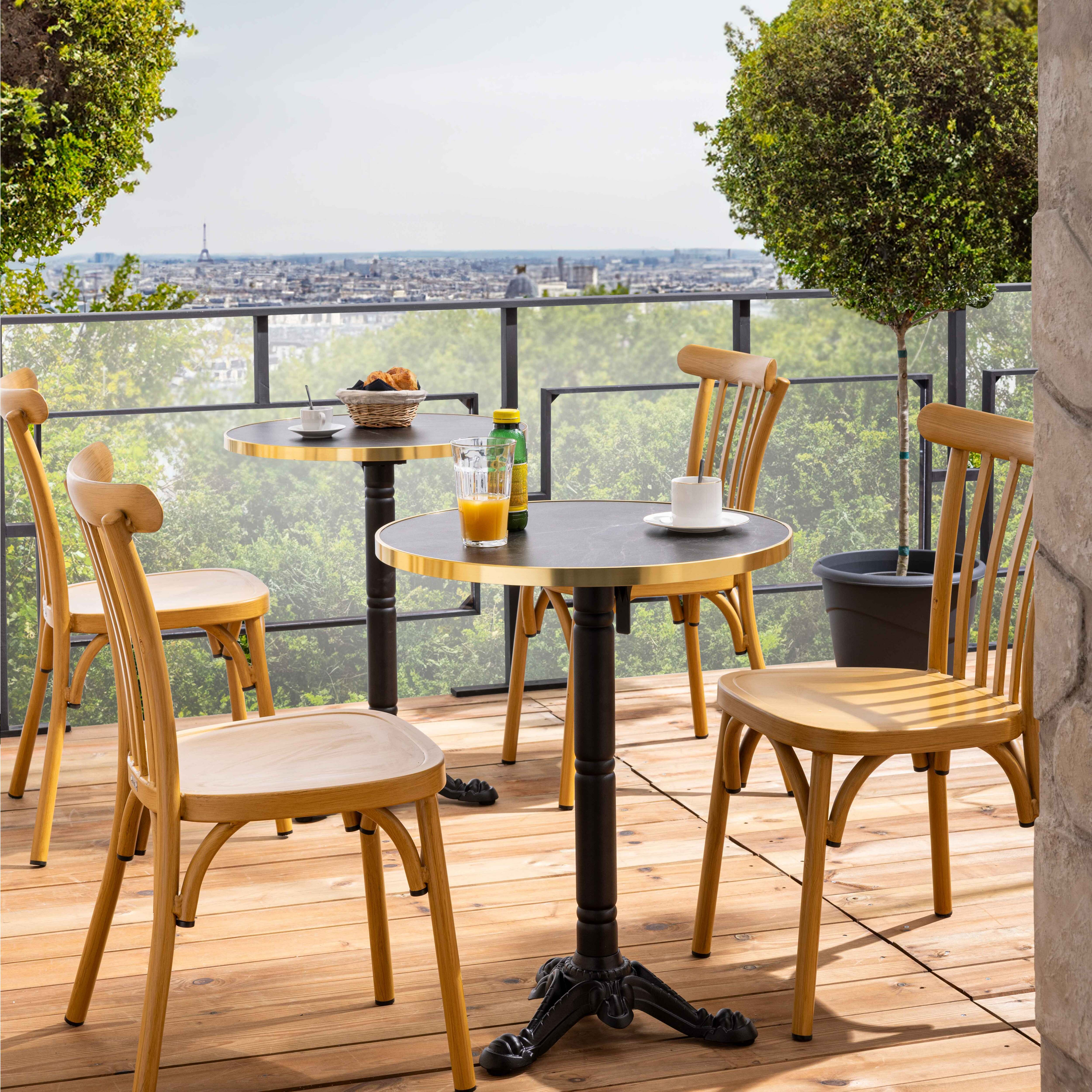 Outdoor-Tische und -Stühle auf einem Holzdeck mit Stadtblick im Hintergrund.