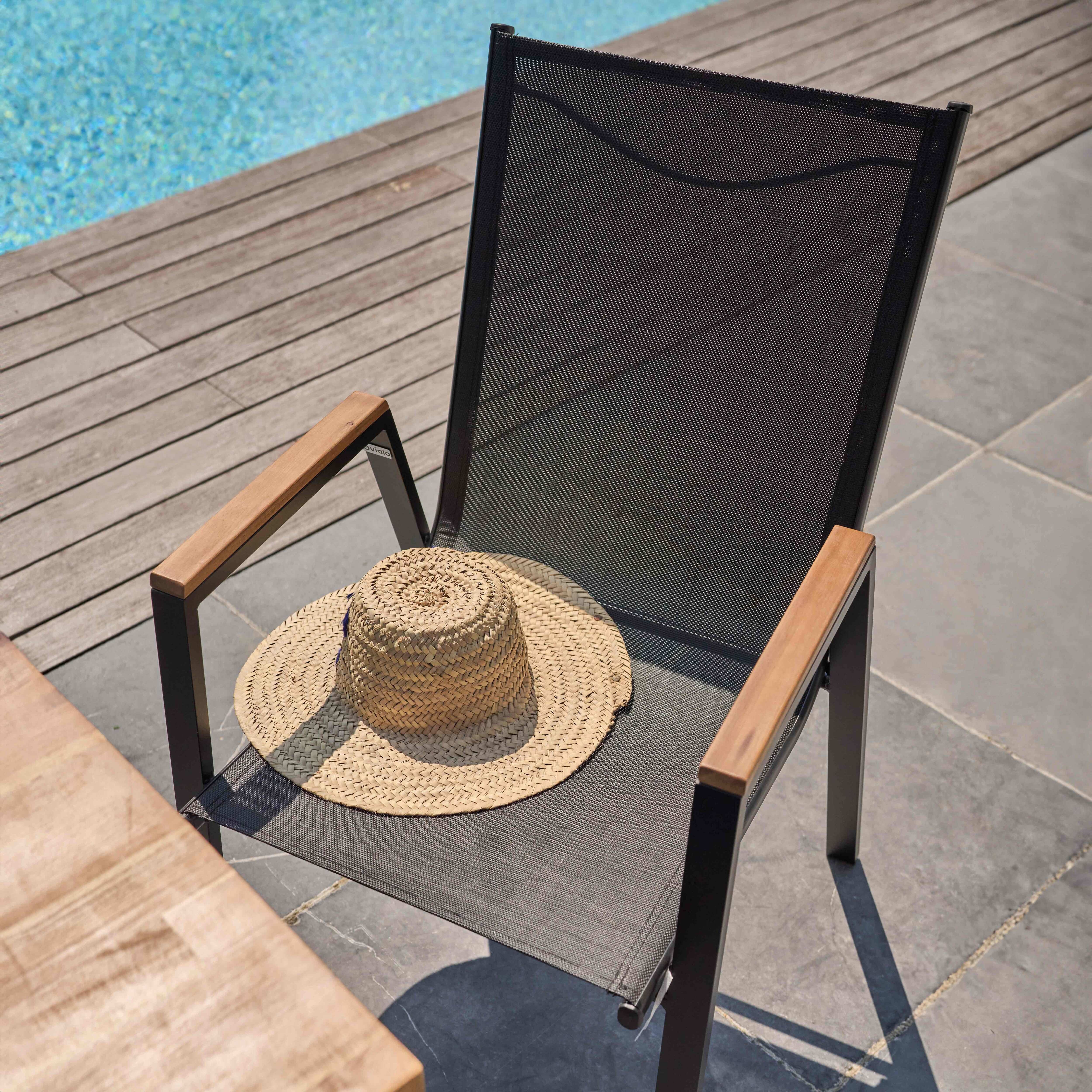 Schwarzer Stuhl mit Hut, neben Pool mit Holzdeck und Steinplatten.