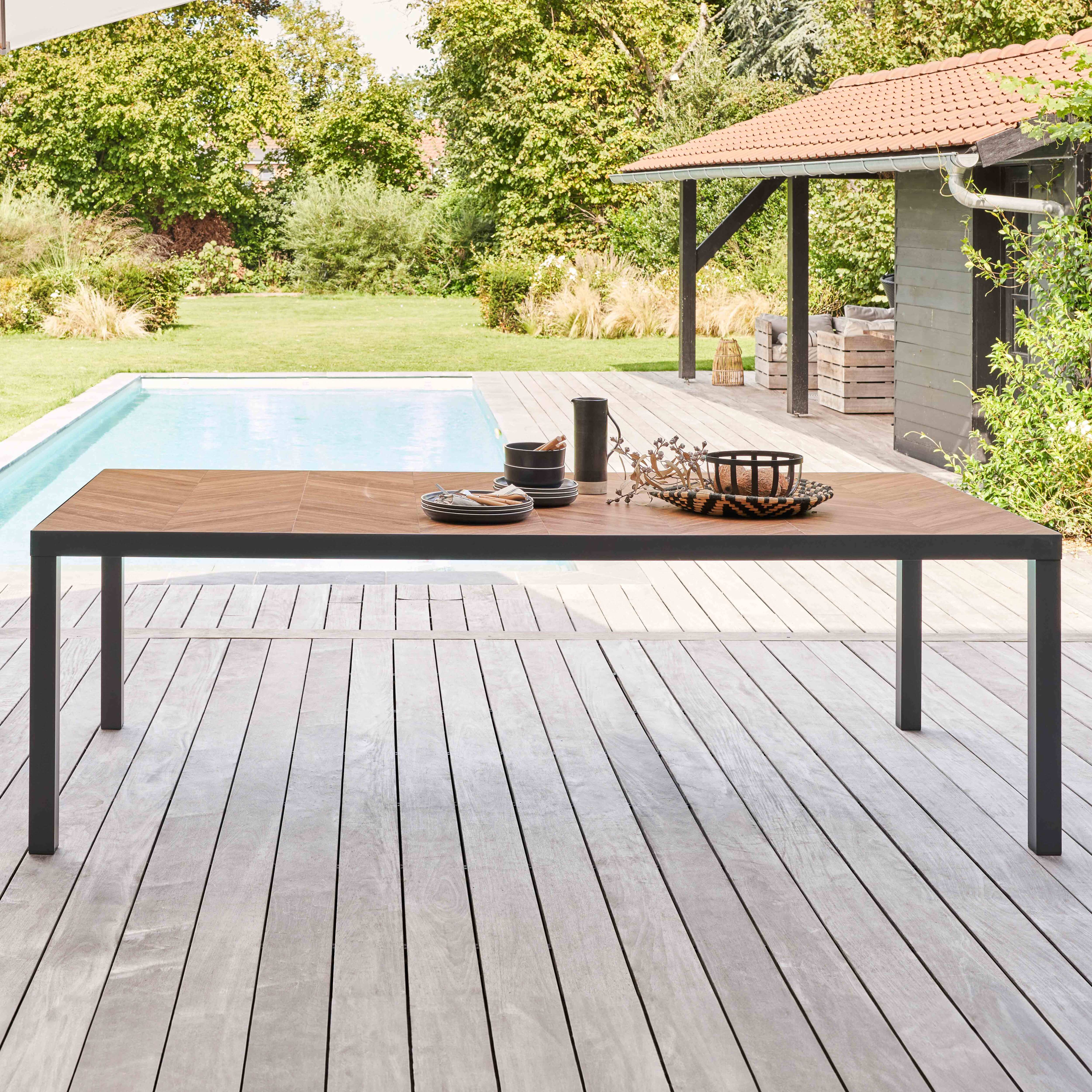 Ein Tisch mit Holzplatte auf einer Terrasse. Der Tisch ist mit Tellern, Tassen und Dekorationen gedeckt.