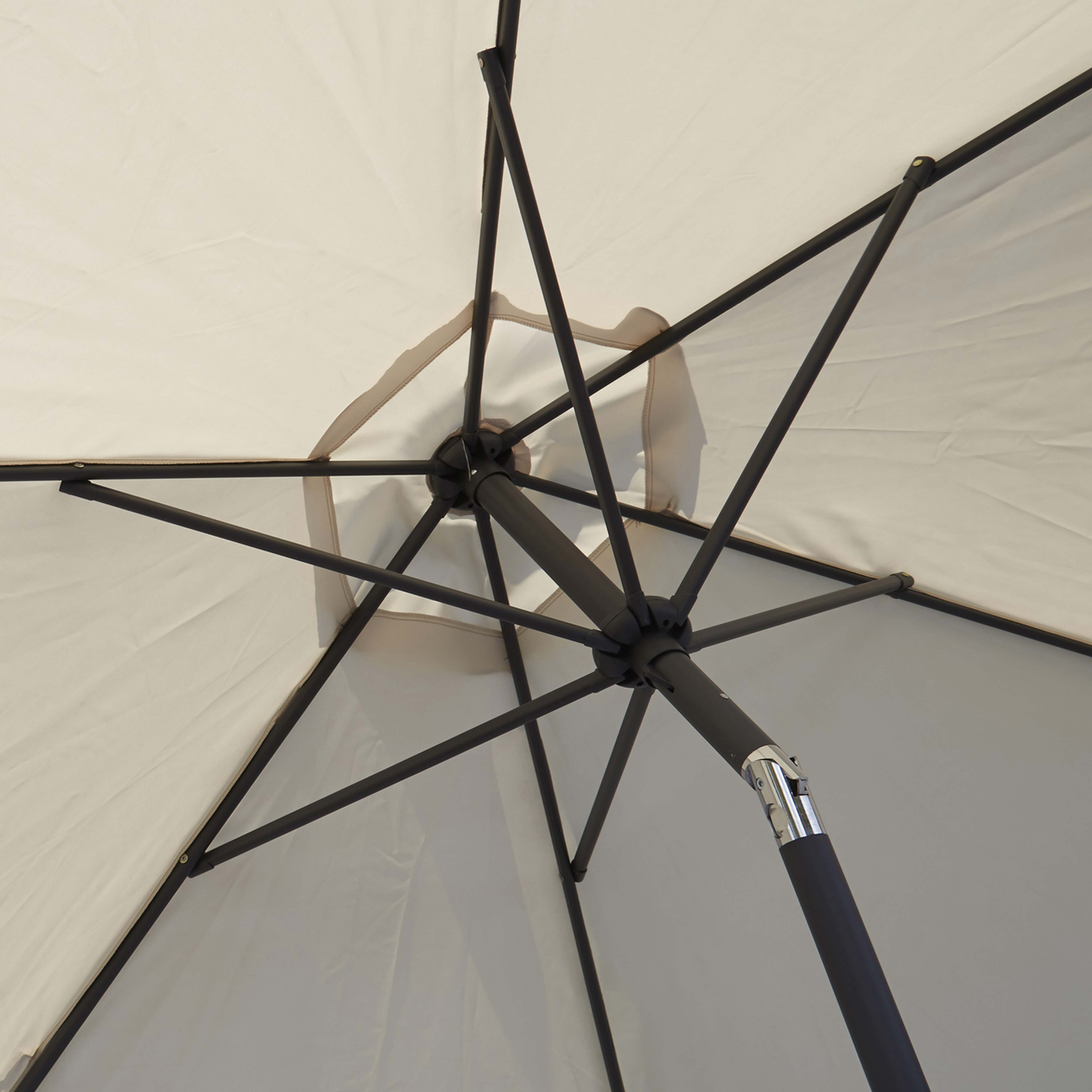 Ein offener Regenschirm von unten, der Rahmen und Baldachin zeigt. Weiße und beige Farben sind sichtbar.