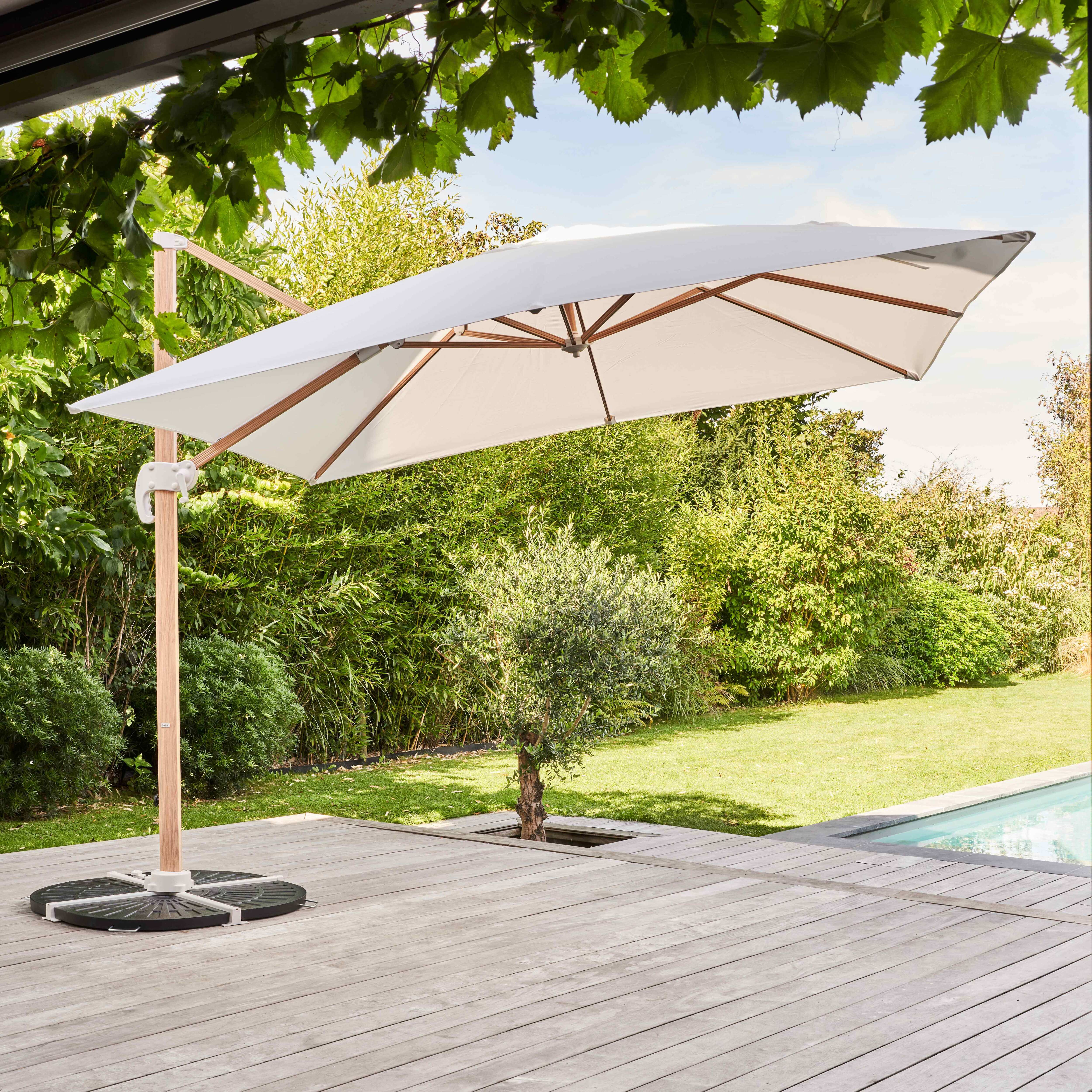 Großer weißer Sonnenschirm im Freien, Holzkonstruktion, auf Holzdeck mit Pflanzen.