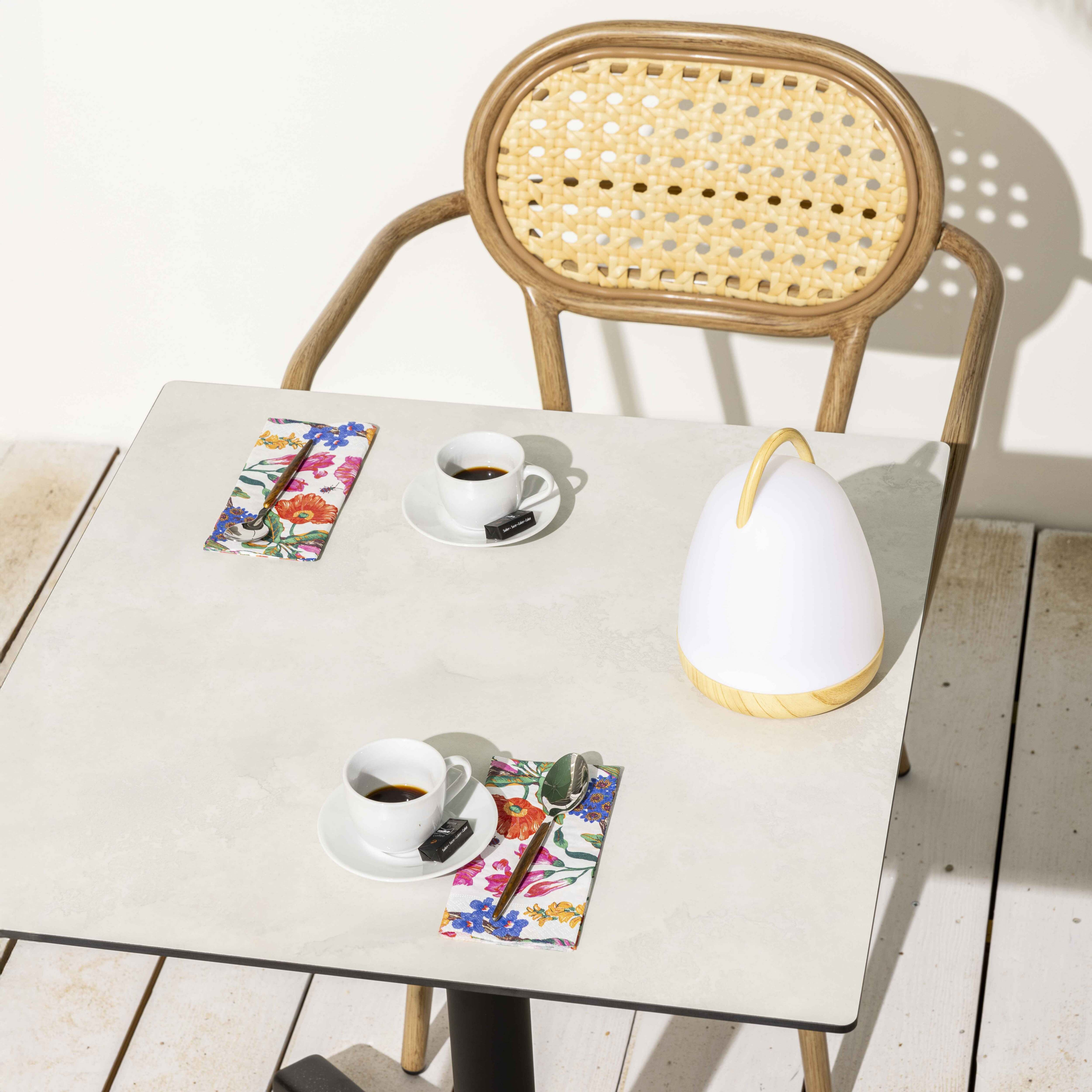 Eine Café-Einstellung mit einem Tisch für zwei Personen, mit Kaffeetassen und einer Lampe.