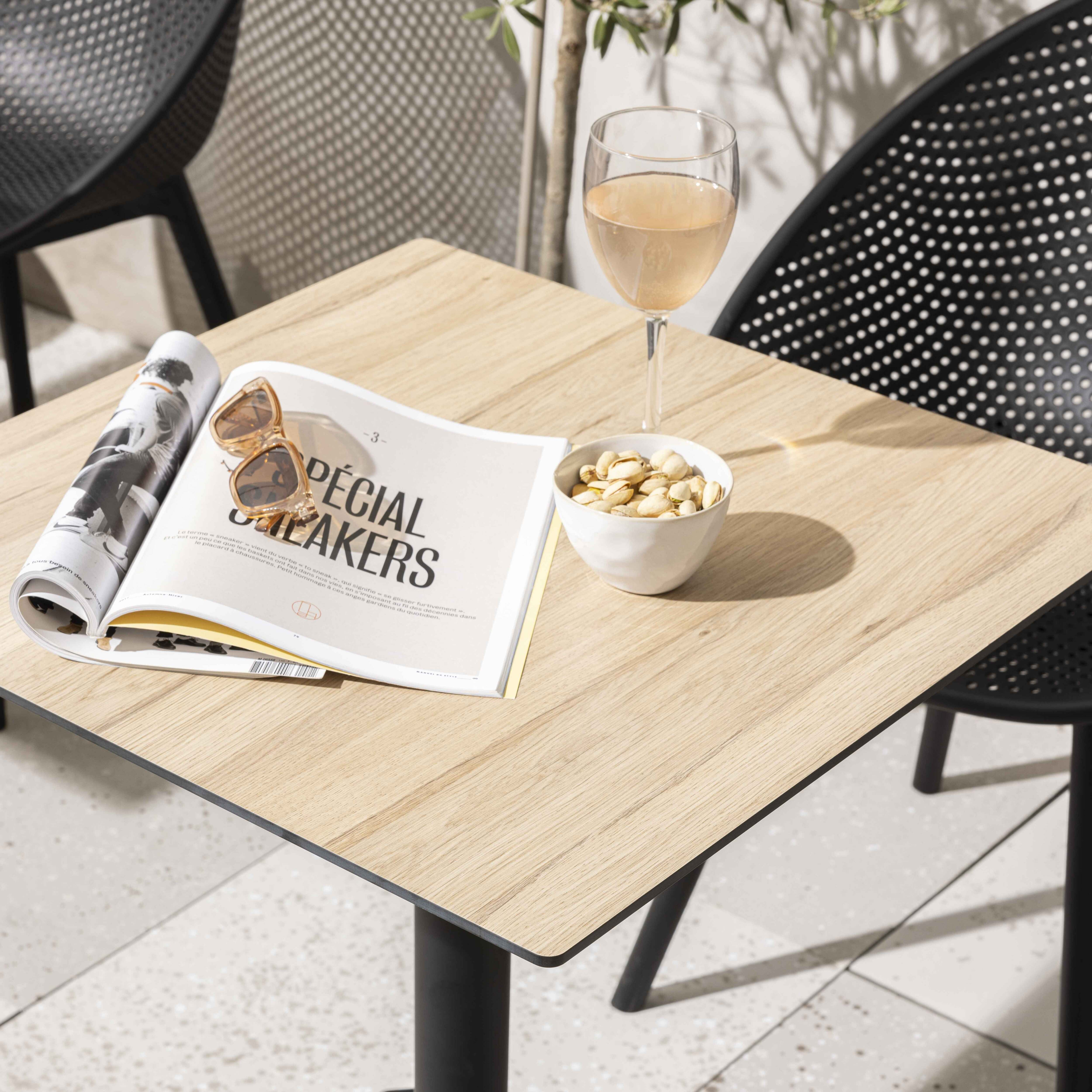Ein Tisch mit einer Zeitschrift, Sonnenbrille, einer Schüssel Nüsse und einem Glas Wein.