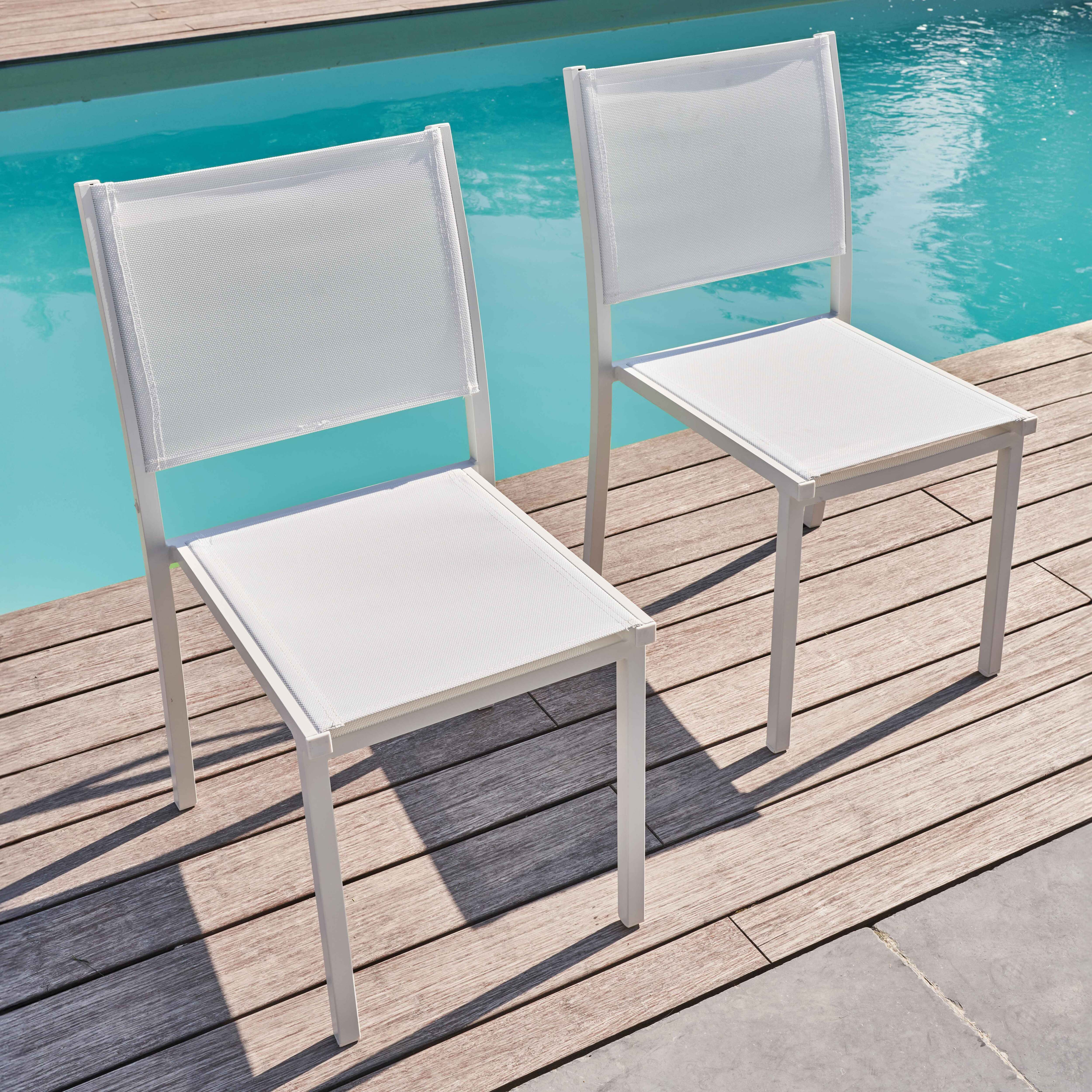 Zwei weiße Stühle mit weißen Rahmen und weißer Netzbespannung, in der Nähe eines Pools.