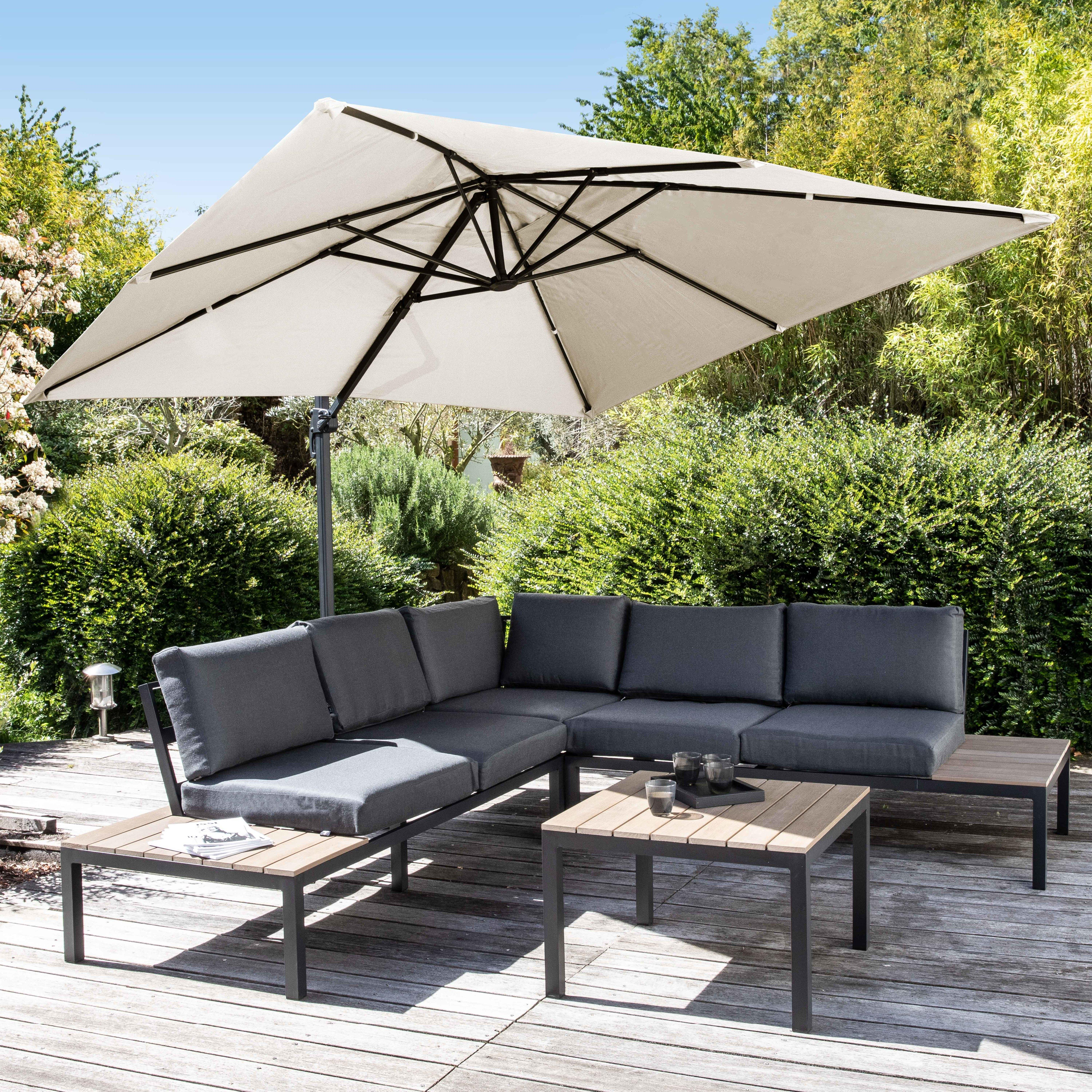 Essgruppe im Freien mit Sofa, Sonnenschirm und zwei Tischen auf Holzterrasse.