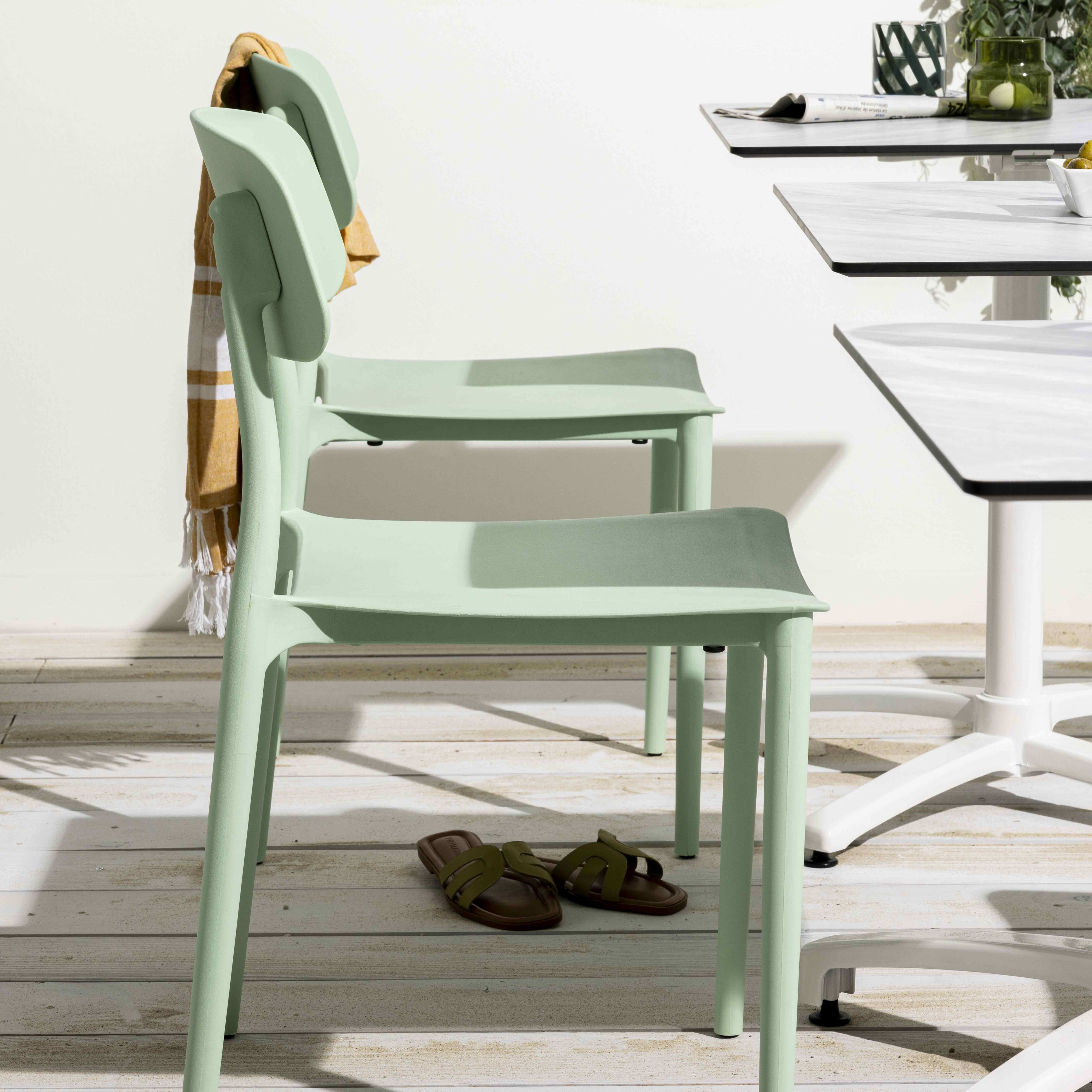 Zwei grüne Stühle in einer Reihe, mit Sandalen auf dem Boden. Ein Tisch ist im Hintergrund.