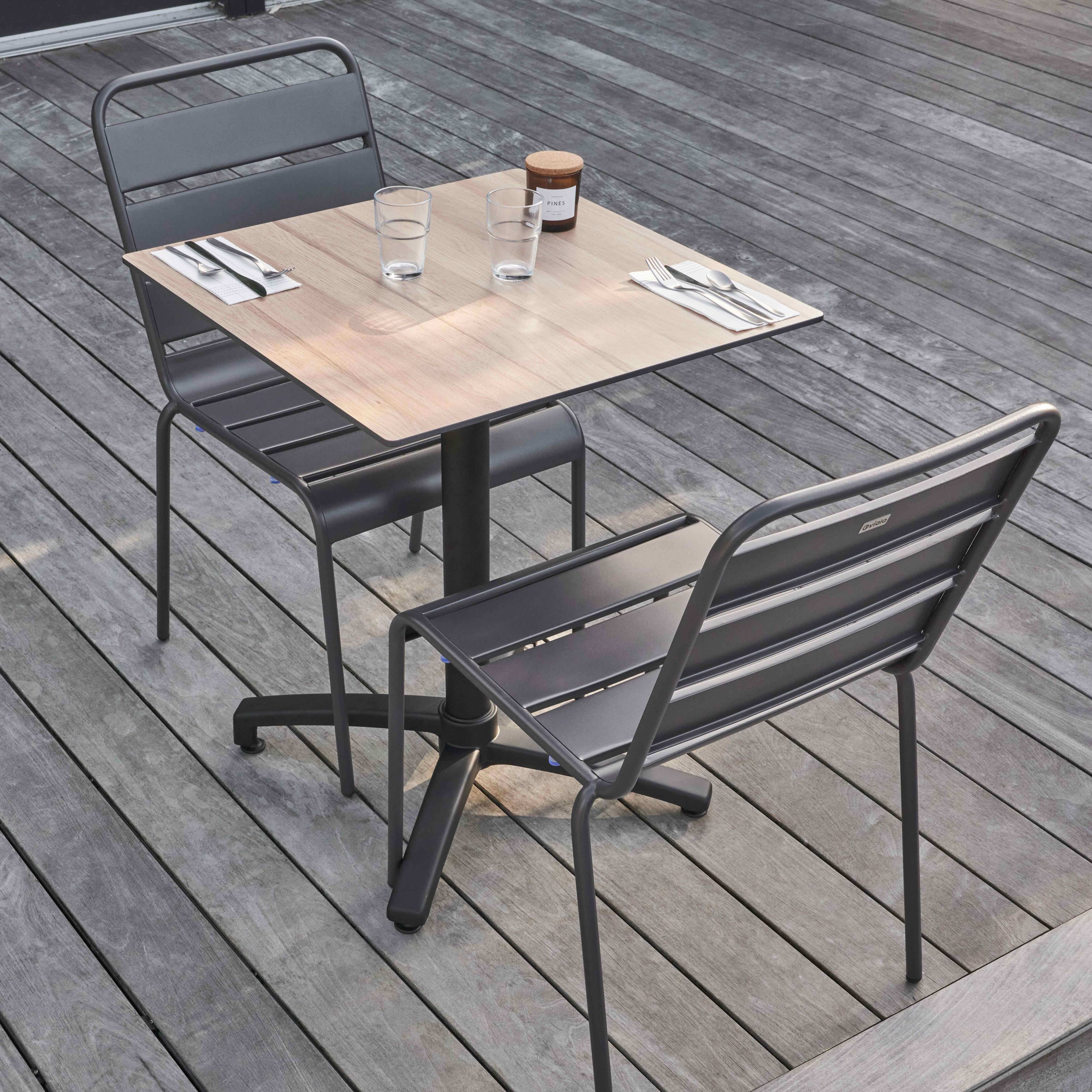 Zwei Stühle und ein quadratischer Tisch mit Holzplatte, auf Holzterrasse.