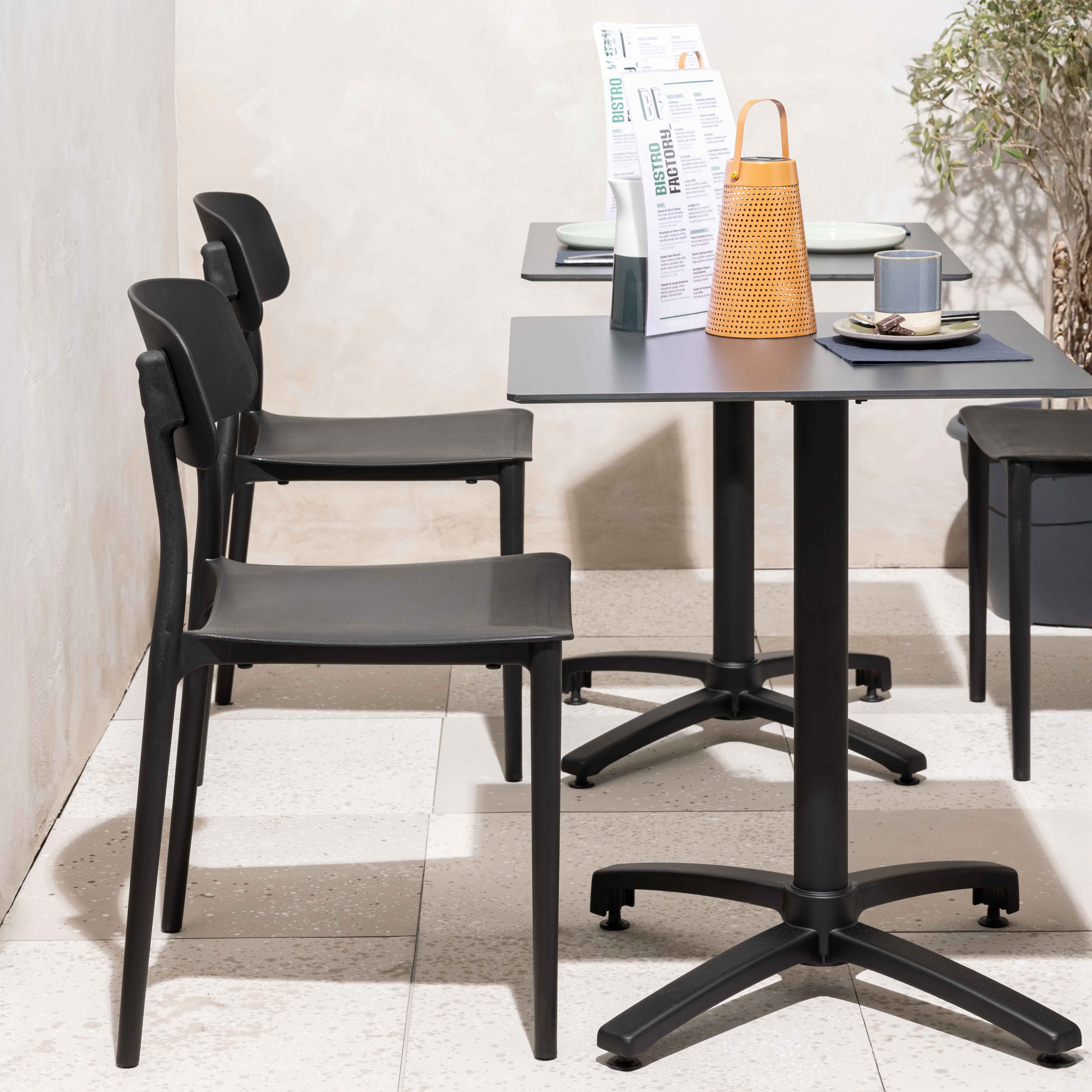 Quadratischer Tisch mit Holzplatte und weißem Sockel mit Dekorationsgegenständen auf einer Terrasse.