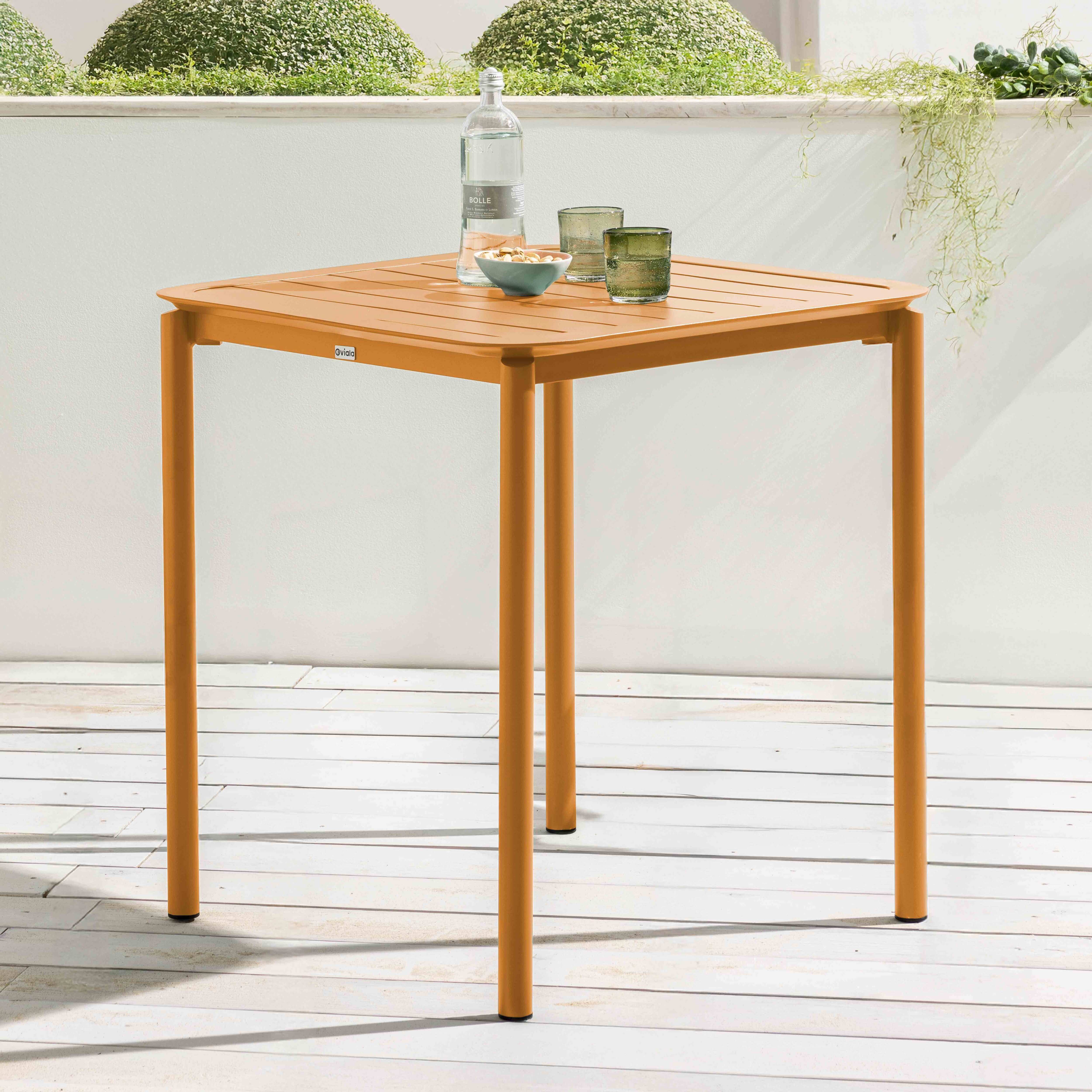 Orangener quadratischer Tisch mit Lattenrost auf einem Holzdeck.