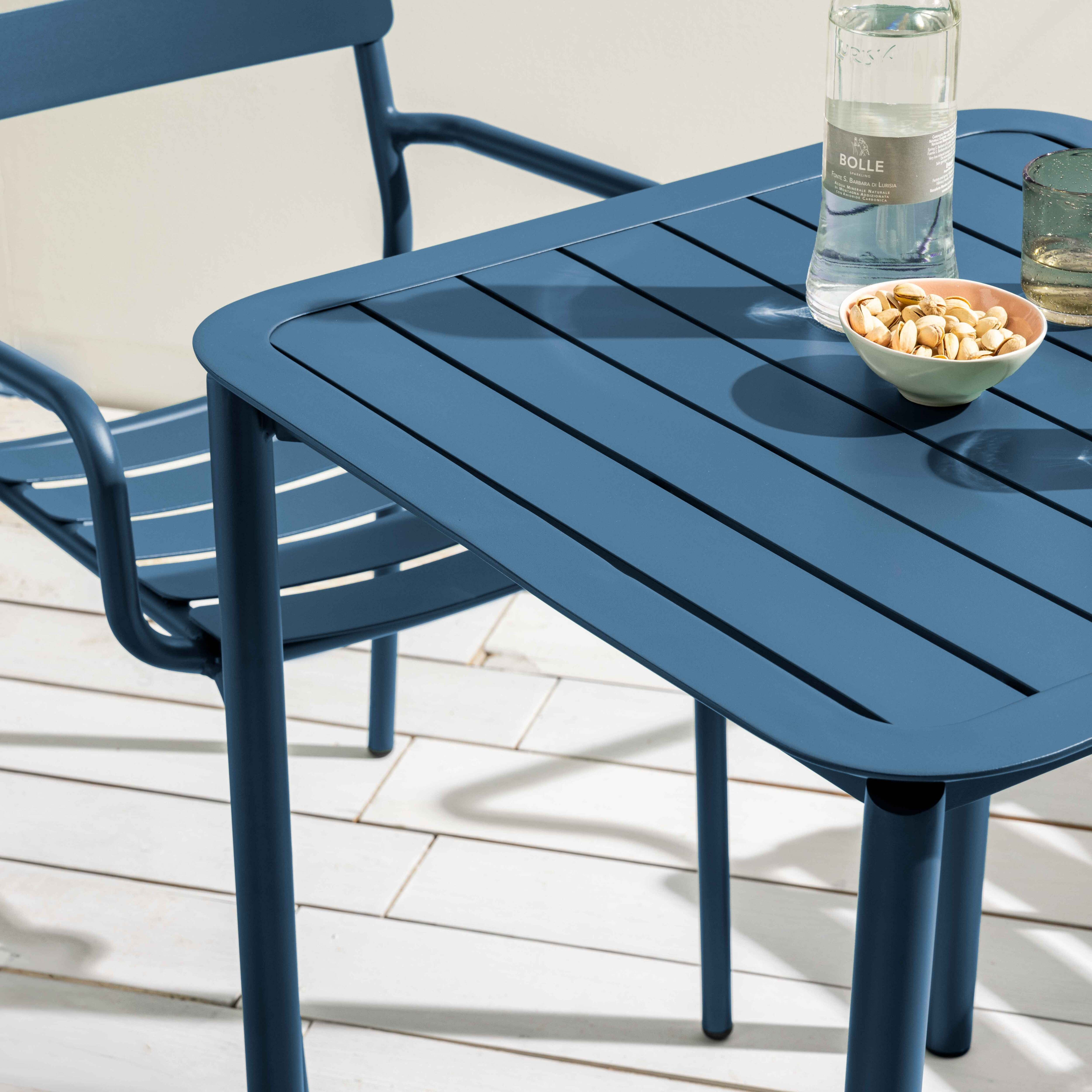 Blauer Tisch mit Stuhl. Es hat eine Wasserflasche, eine Schüssel mit Nüssen und ein Glas.