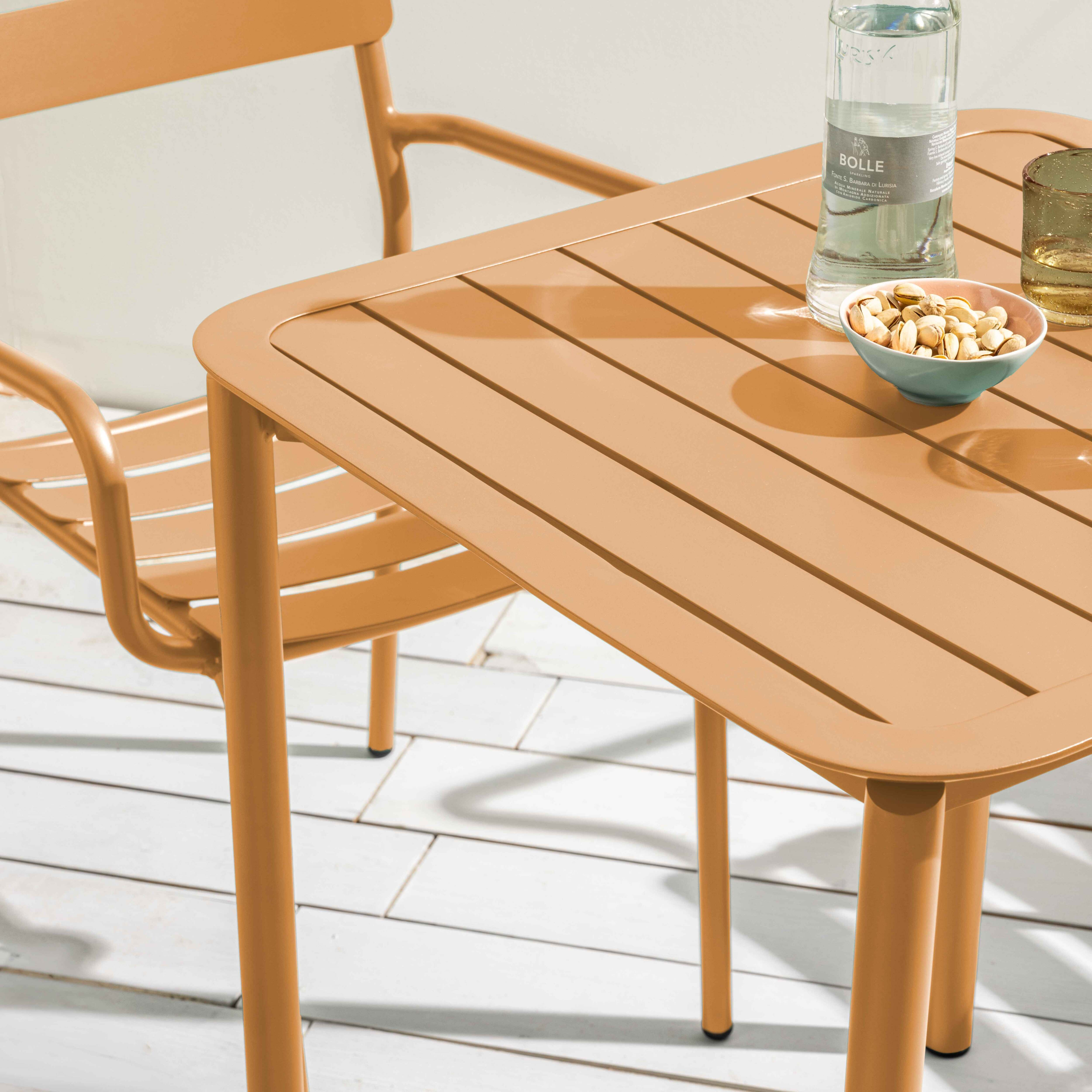 Orangener Gartentisch mit Stuhl, Wasserflasche, Schüssel mit Nüssen und Glas.