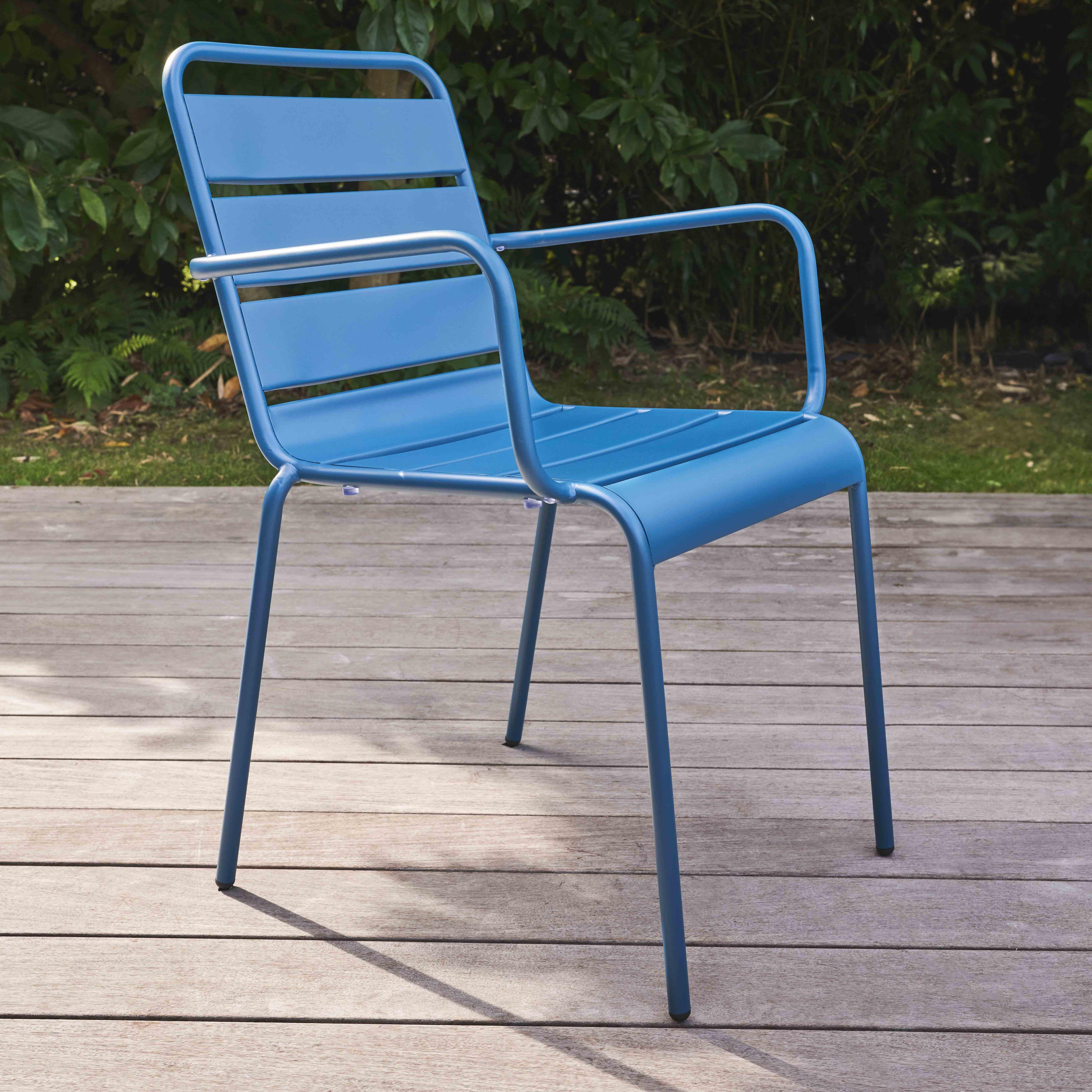 Blauer Gartenstuhl auf Holzterrasse, mit Bäumen im Hintergrund.