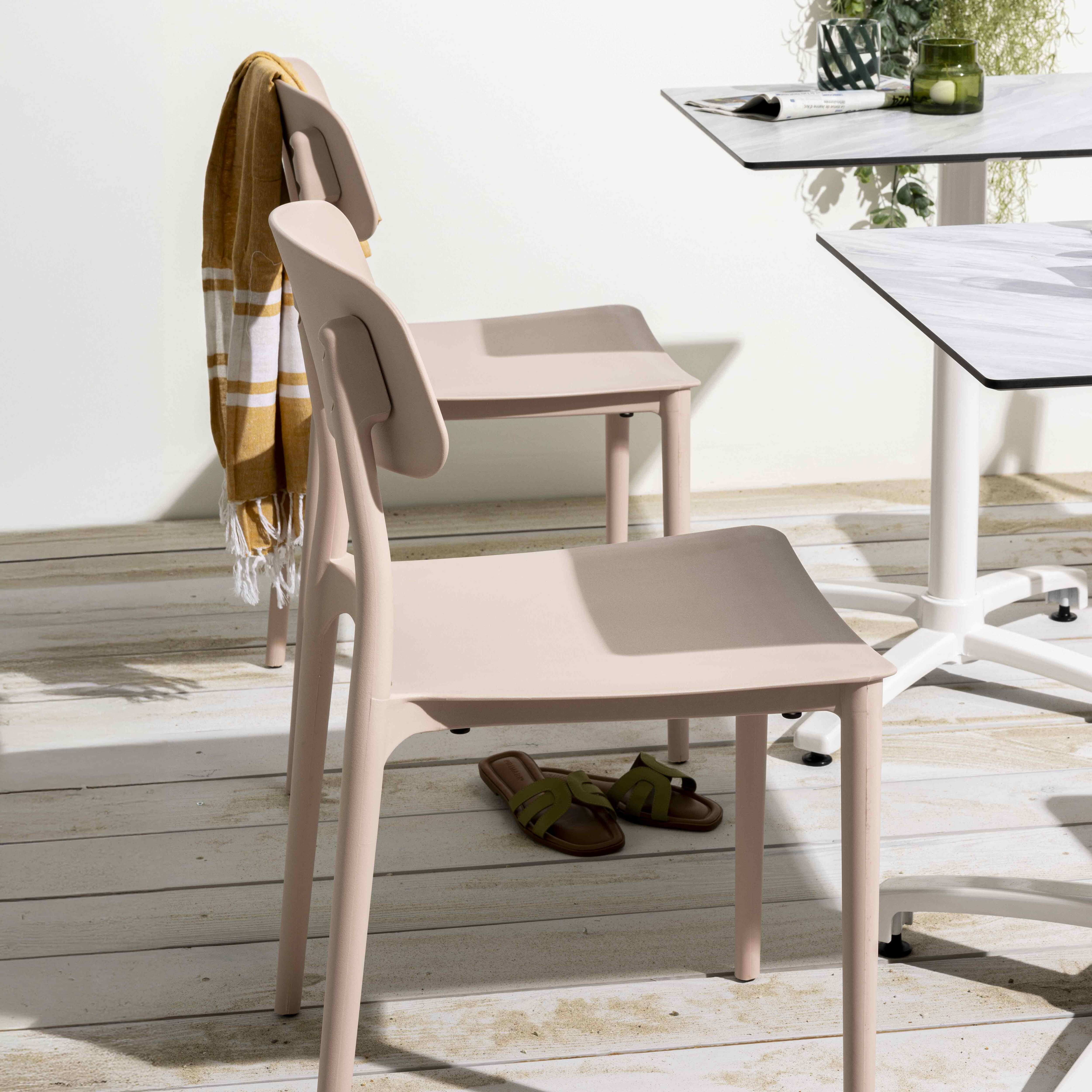 Rosa Stühle, Tisch mit Marmorplatte, Handtuch und Sandalen auf Holzboden, sonniger Tag.