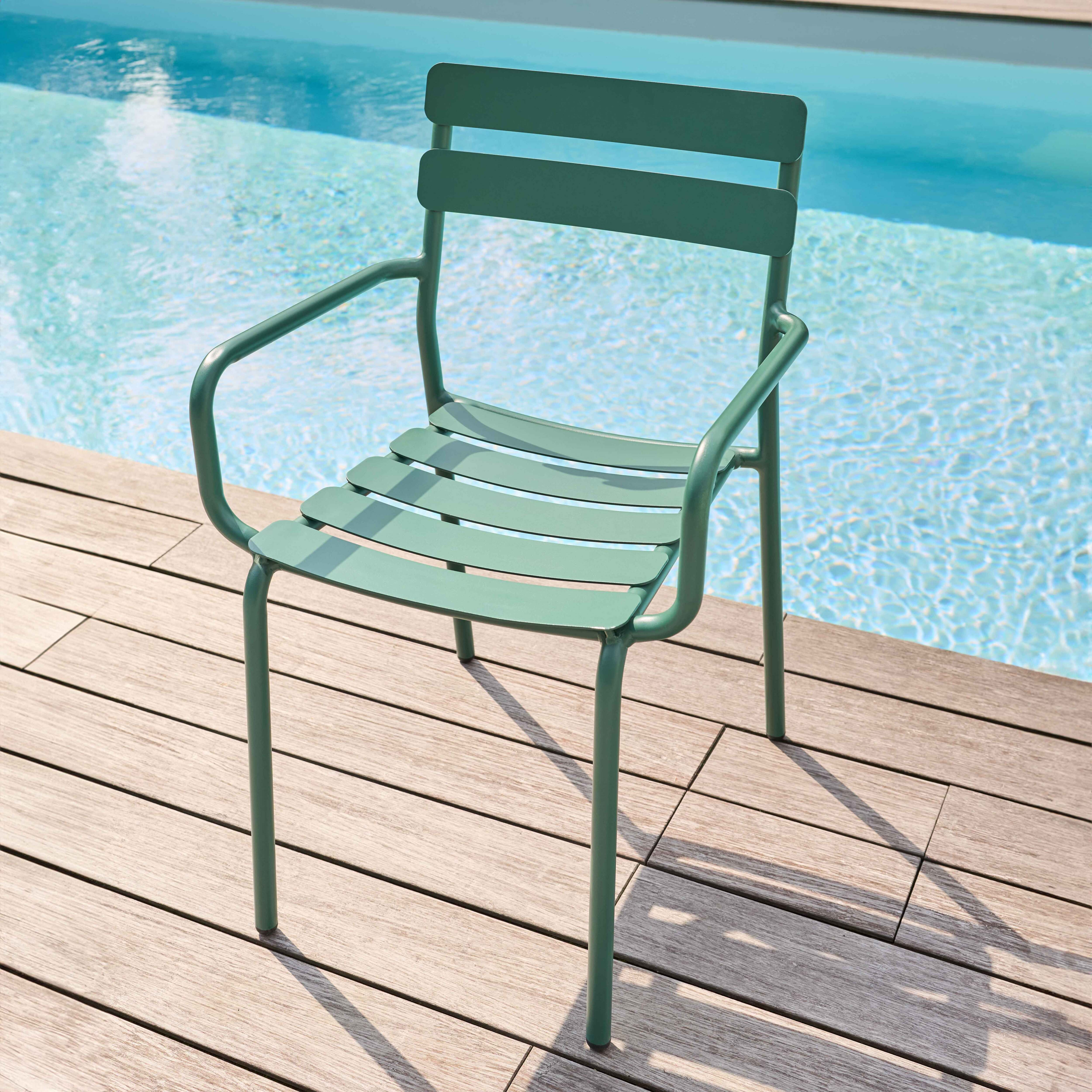 Grüner Stuhl mit Armlehnen, in der Nähe eines Pools. Der Stuhl steht auf einem Holzdeck.