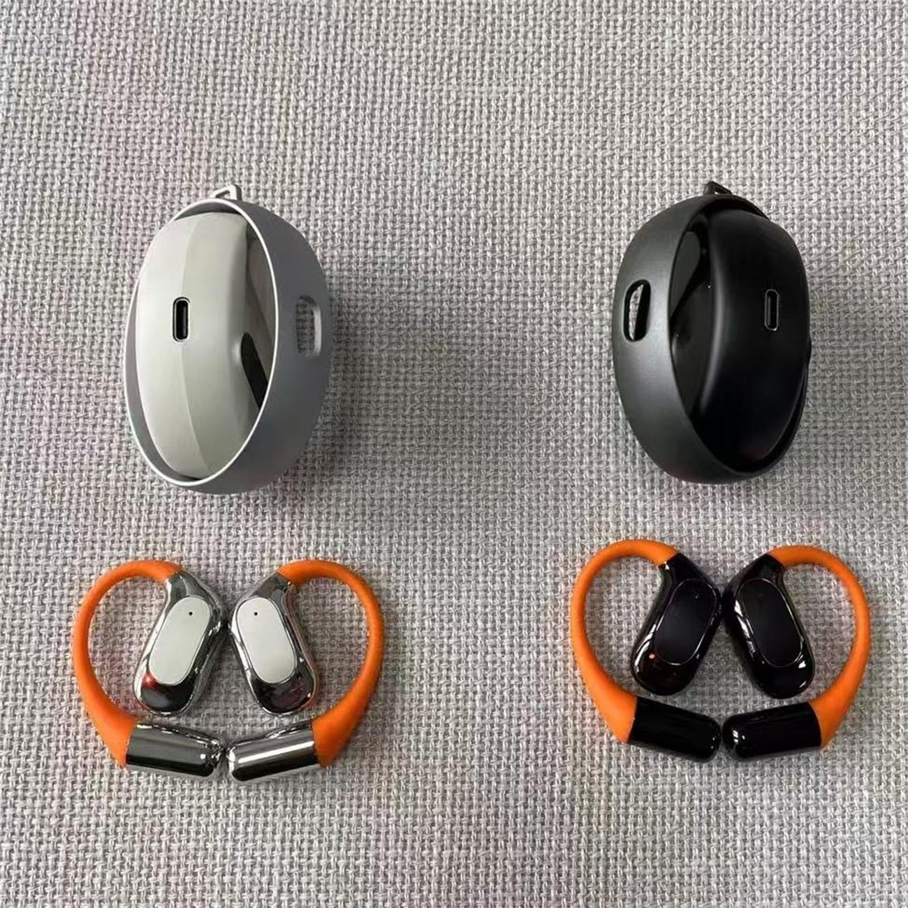 Ohrhörer und Ladeetuis in Grau und Schwarz, orangefarbene Nackenbügel-Ohrhörer.