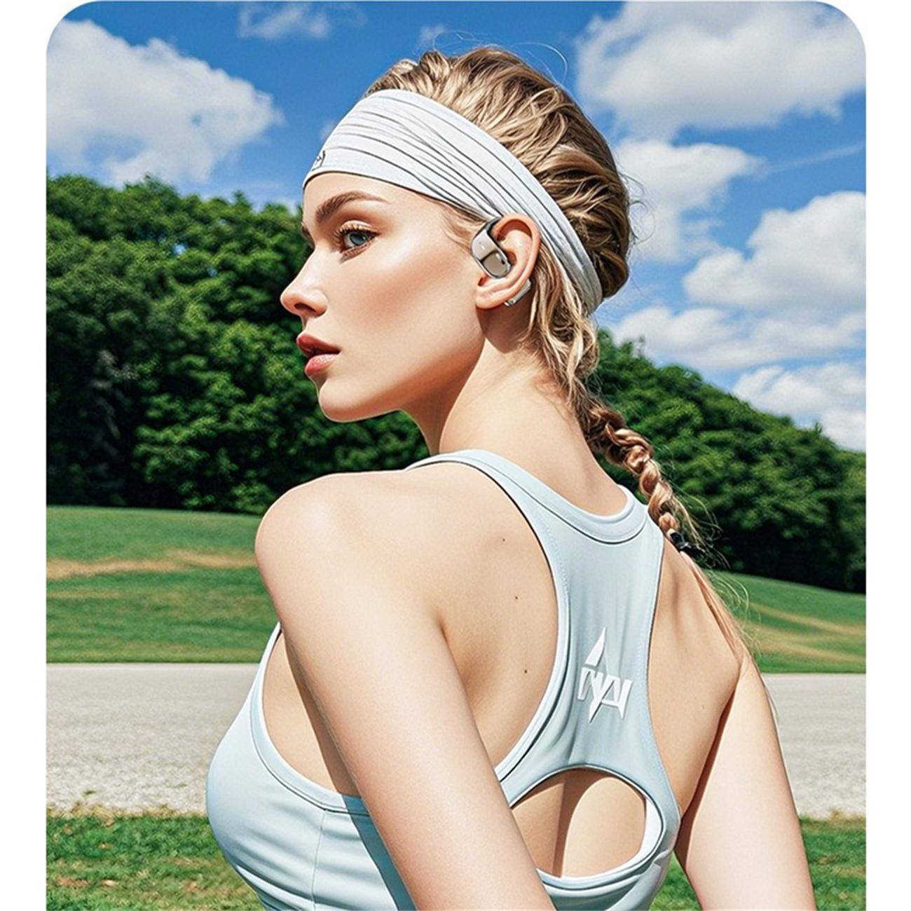Frau mit Stirnband und Tanktop, Knochenschallkopfhörer tragend, mit klarem blauem Himmel im Hintergrund.