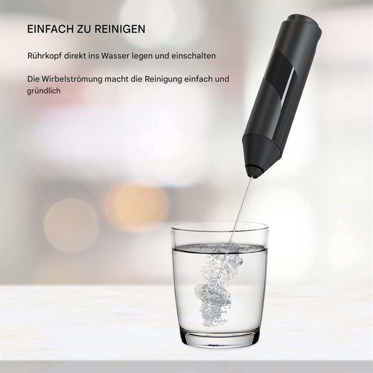 Schwarzer Milchaufschäumer in einem Wasserglas. Blasen bilden sich während des Betriebs.