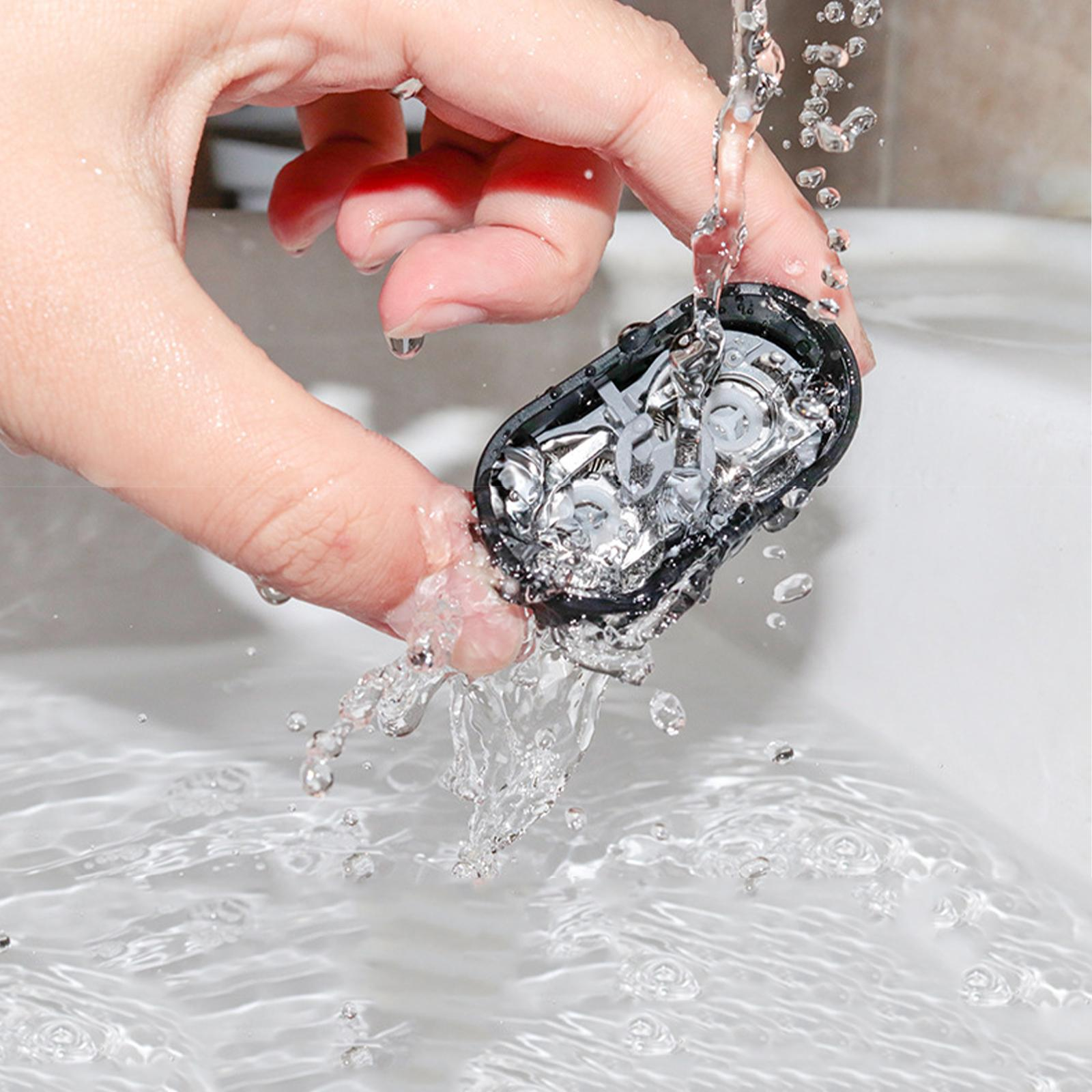 Hand hält ein schwarzes Gerät, Wasser fließt darüber in ein weißes Waschbecken.