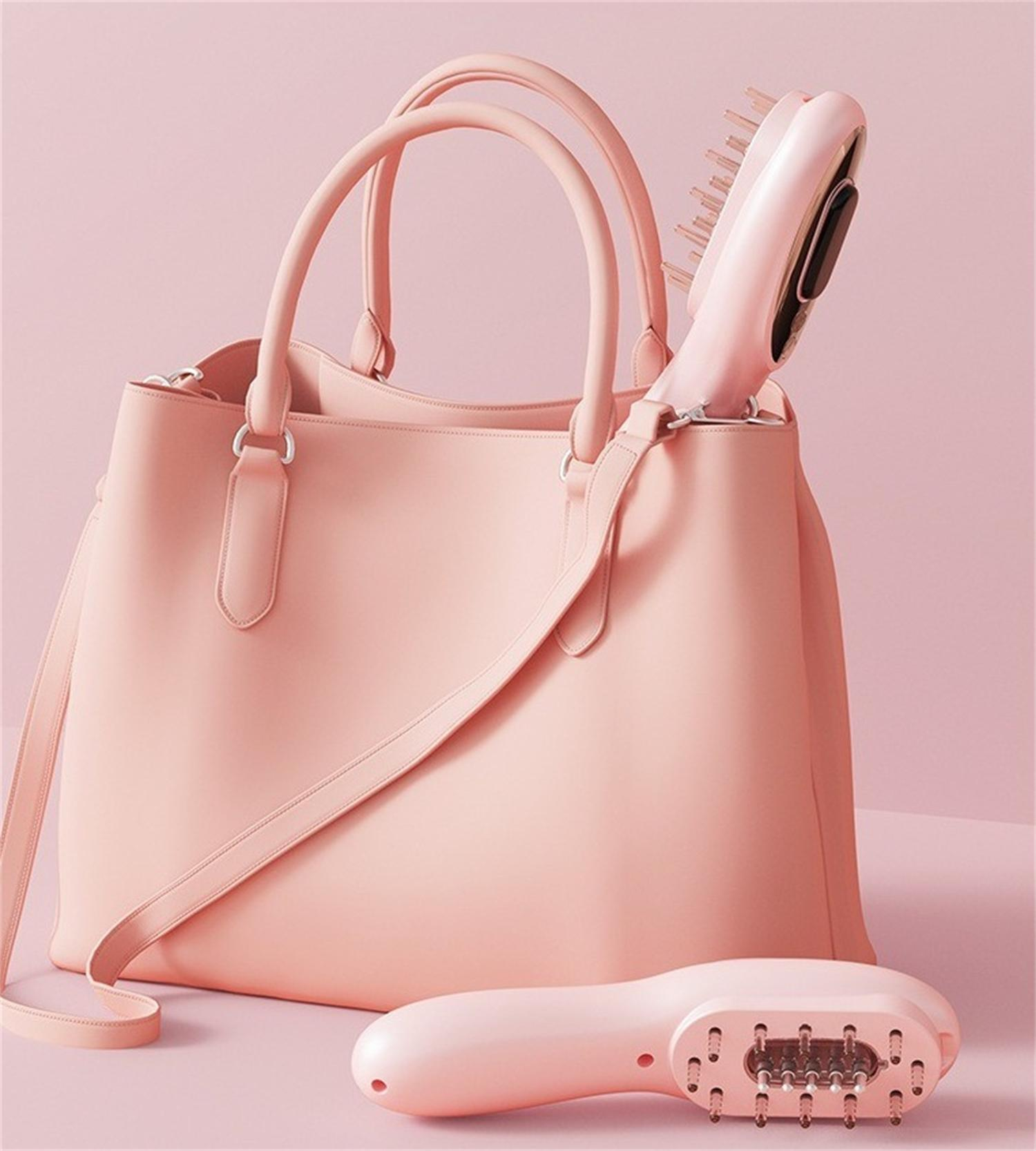 Eine rosa Handtasche mit einer Bürste darin und eine Bürste, die auf der Oberfläche liegt, alles auf rosa Hintergrund.