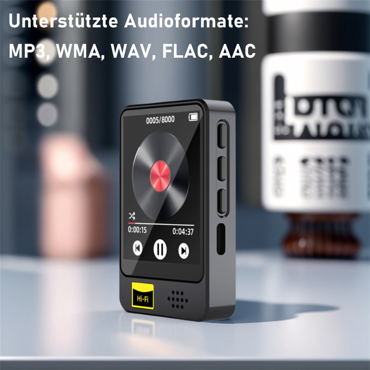 Schwarzer Musikplayer mit Bildschirm, auf einem Tisch. Weißer Hintergrund mit unscharfen Objekten.